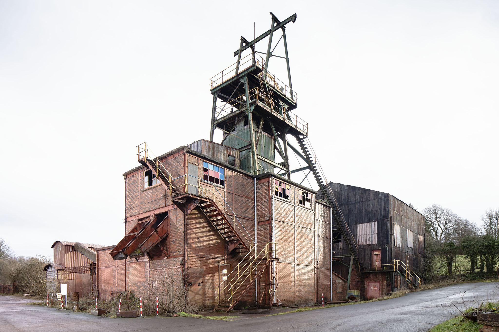 Florence Mine in West Cumbria is one of the best-surviving mining sites of any type nationally and is the best-surviving example of an iron mining pit head in England: it retains a full suite of buildings complete with nearly all of its machinery and equipment. From the mid-19th century, iron mining fundamentally altered Western Cumbria and the Furness peninsular, making a significant contribution to the national economy. However, site clearances following industrial decline in the second half of the 20th century, has left few surviving remains of the industry. Florence Mine is believed to have been the last iron mine to close in Europe and was last worked in 2007. Hematite iron ore from the mine is used for the pigment Egremont Red, still found in some lipsticks today.
Listed Grade II