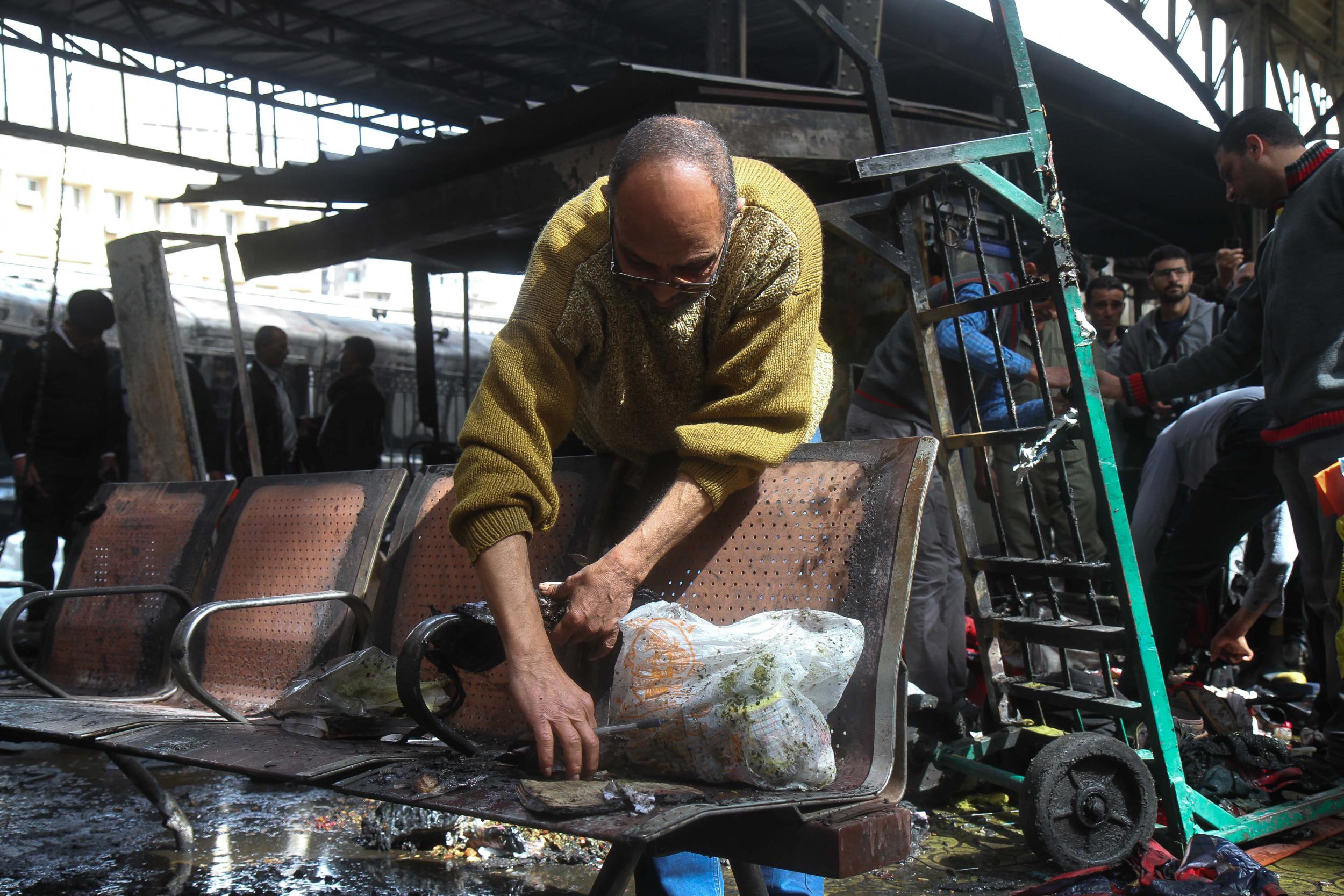 A man clears charred objects at the scene of a fiery train crash at the Egyptian capital Cairo's main railway station