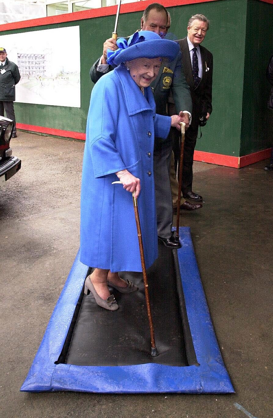 The Queen Mother uses a disinfected mat as she arrives at Sandown Park in Surrey for the racing in 2001