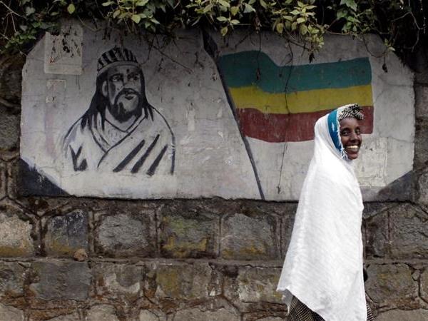 An Ethiopian woman walks past a mural depicting Ethiopia's Emperor Tewodros II in Addis Ababa, Ethiopia.