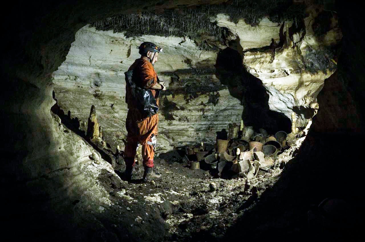 An archaeologist stands next to pre-columbian artifacts in a cave at the Mayan ruins of Chichen Itza