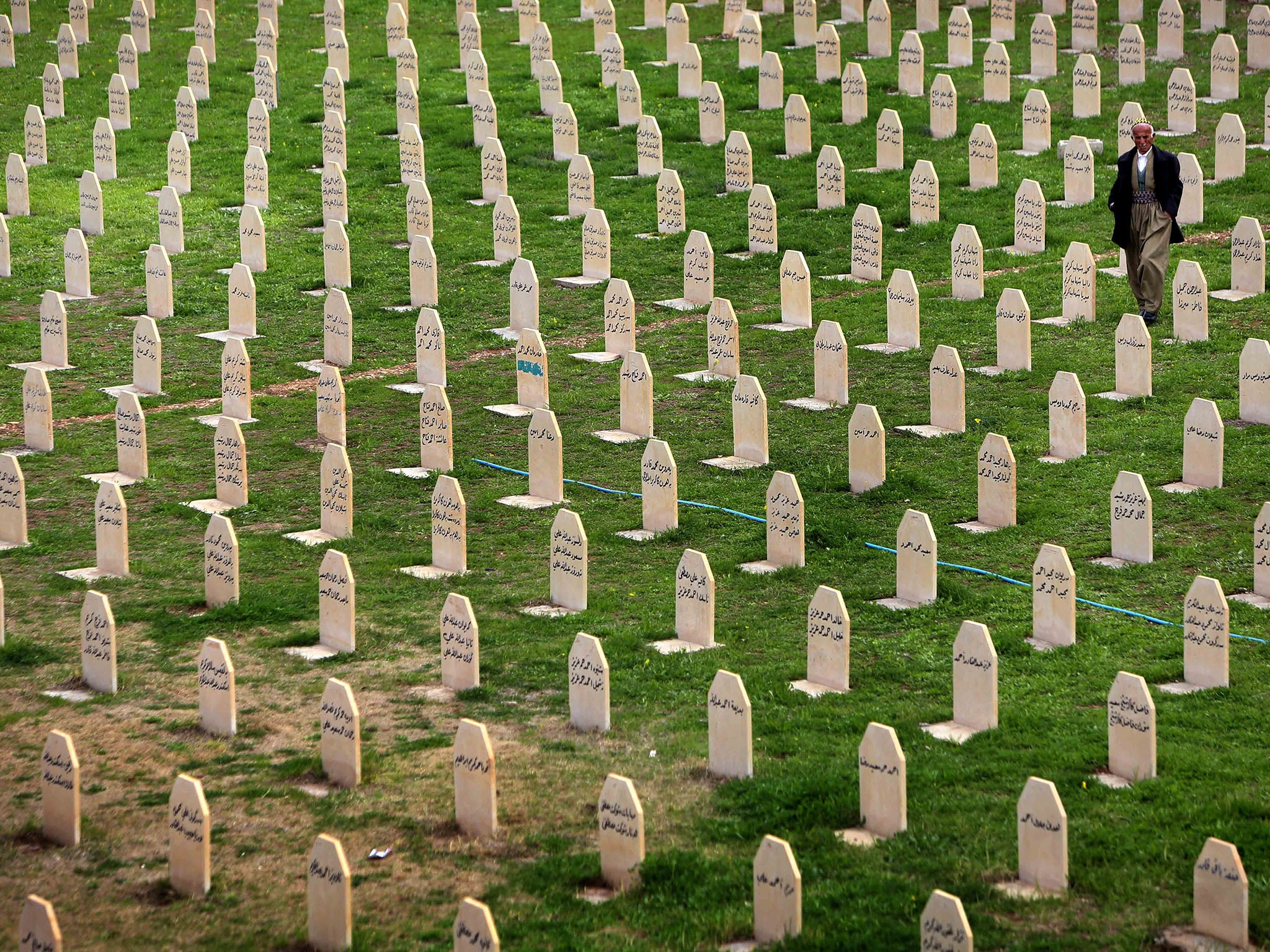 An Iraqi Kurd man walks past grave stones for the victims of a gas attack by Saddam Hussein in 1988