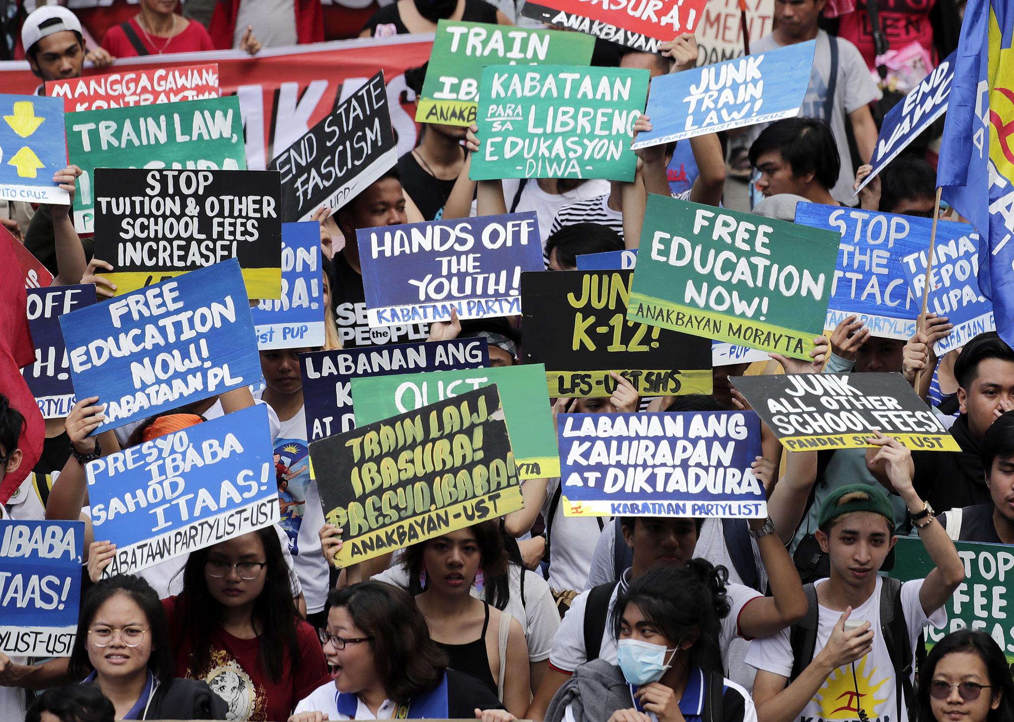 Campaigners hold placards during a rally marking the day in Manila