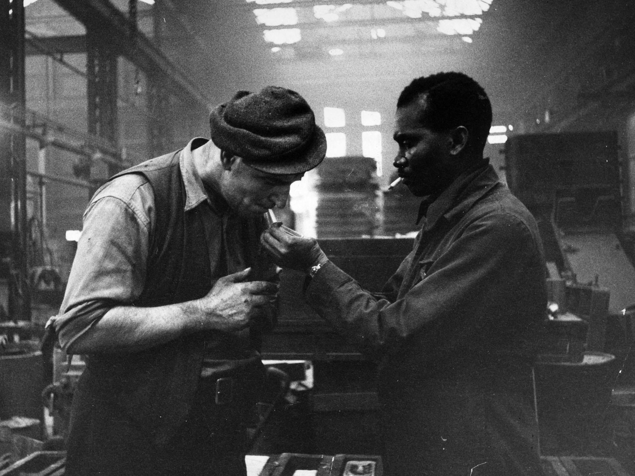 Kwessi Blankson gives a light to workmate Jack White in a Birmingham factory