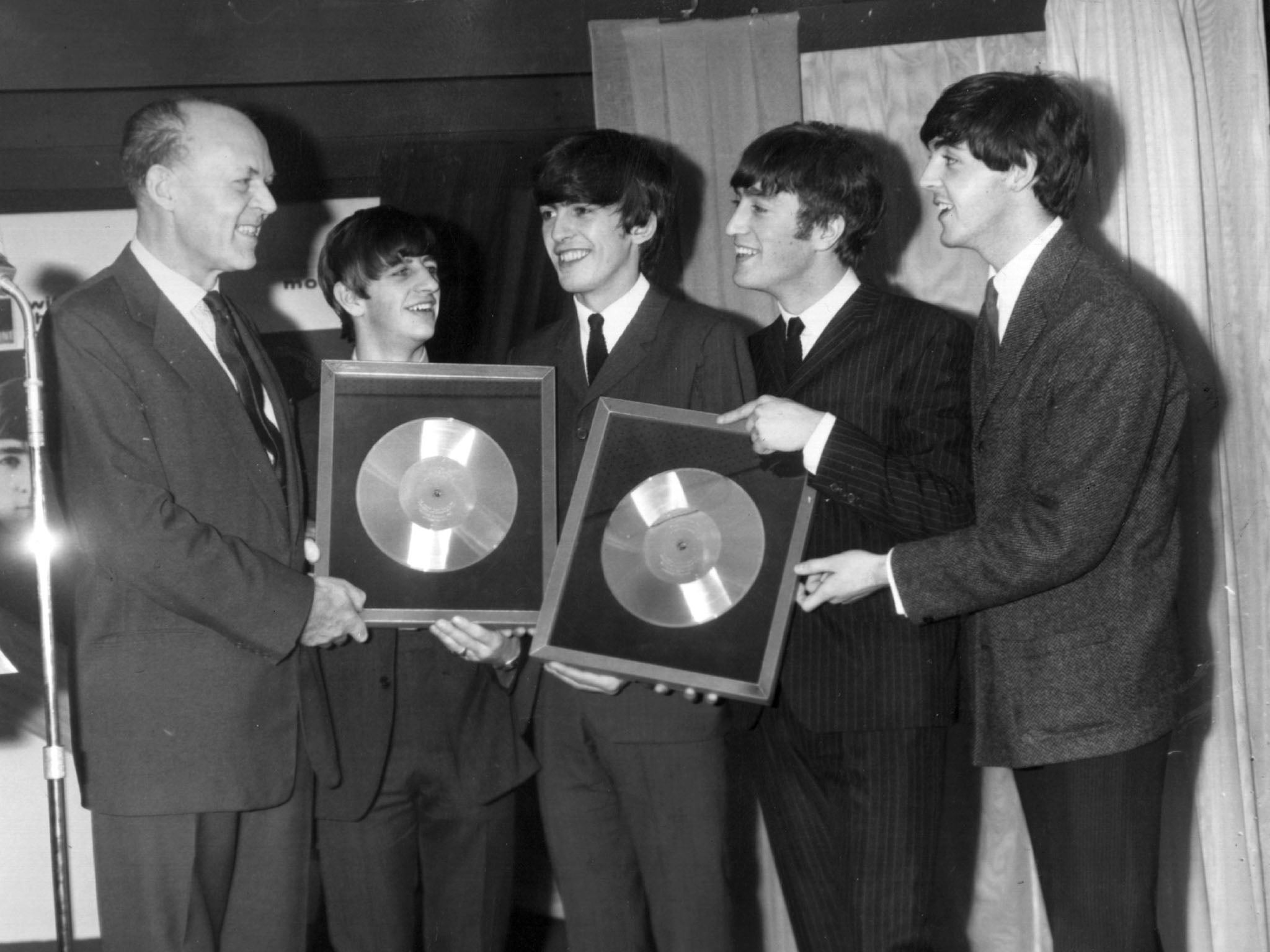 Sir Joseph Lockwood, chair of EMI, presents The Beatles with two silver discs to mark the 250,000 plus sales of their records “Please, Please Me” and “With The Beatles” (Getty Images)