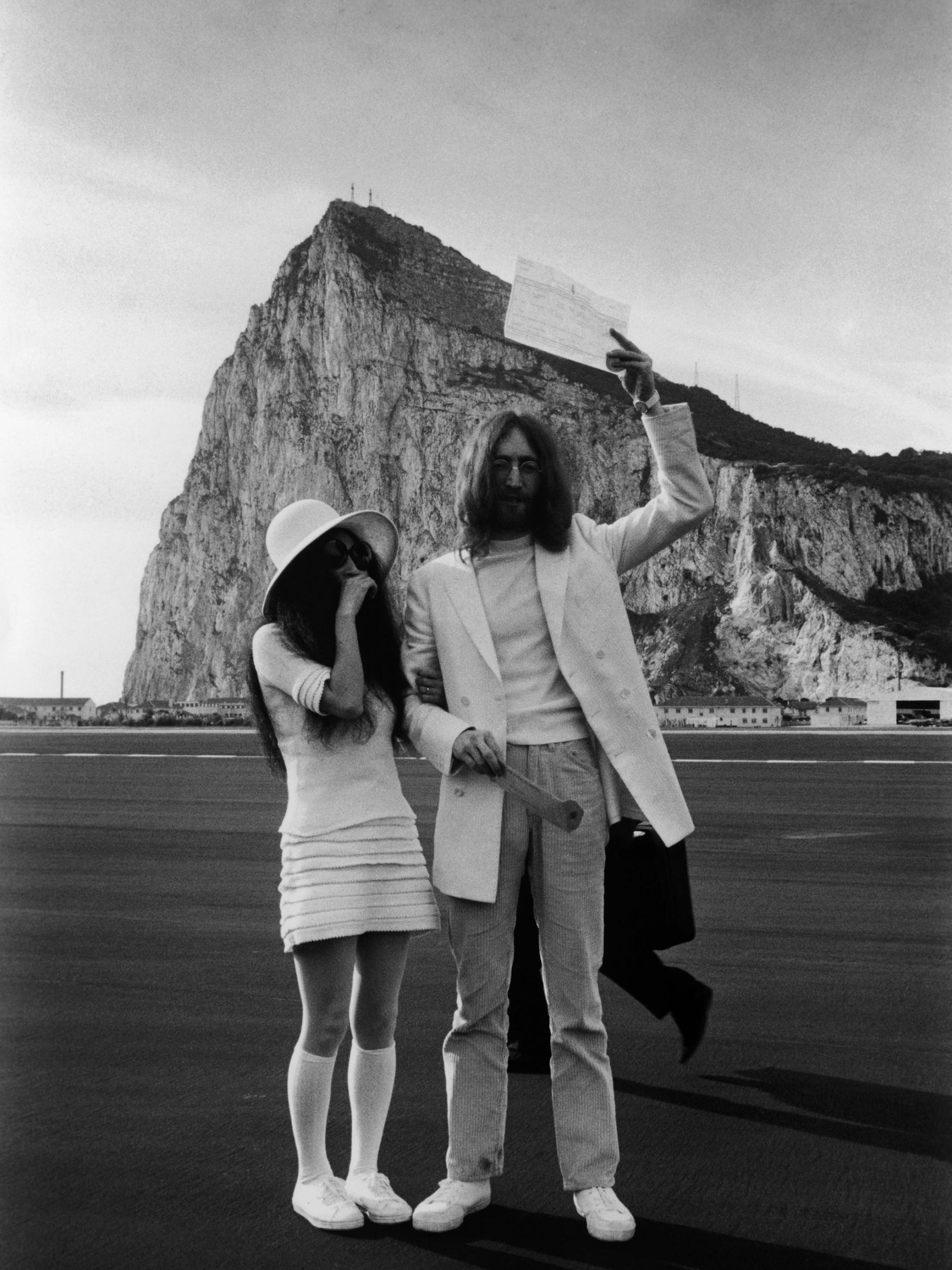 John Lennon and Yoko Ono, both dressed in white, hold up their marriage certificate after their wedding in Gibraltar in 1969 (Getty)