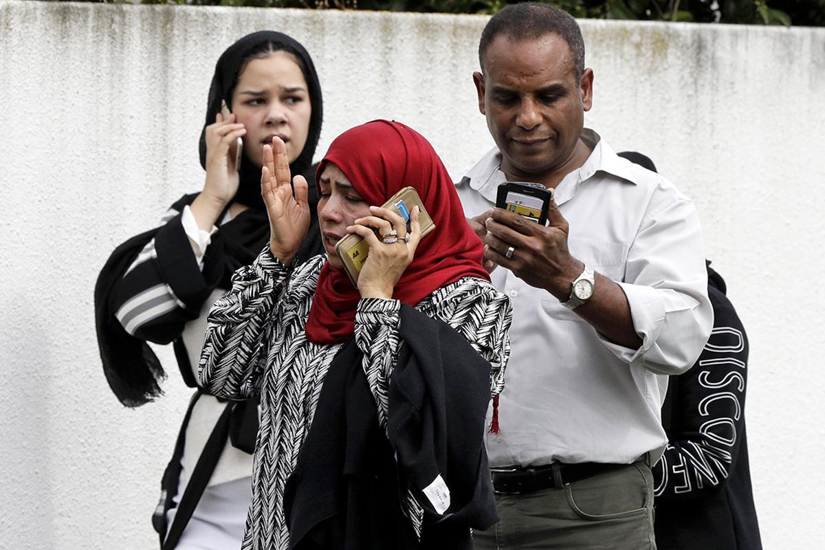 People outside the mosque speak on their phones after the attack