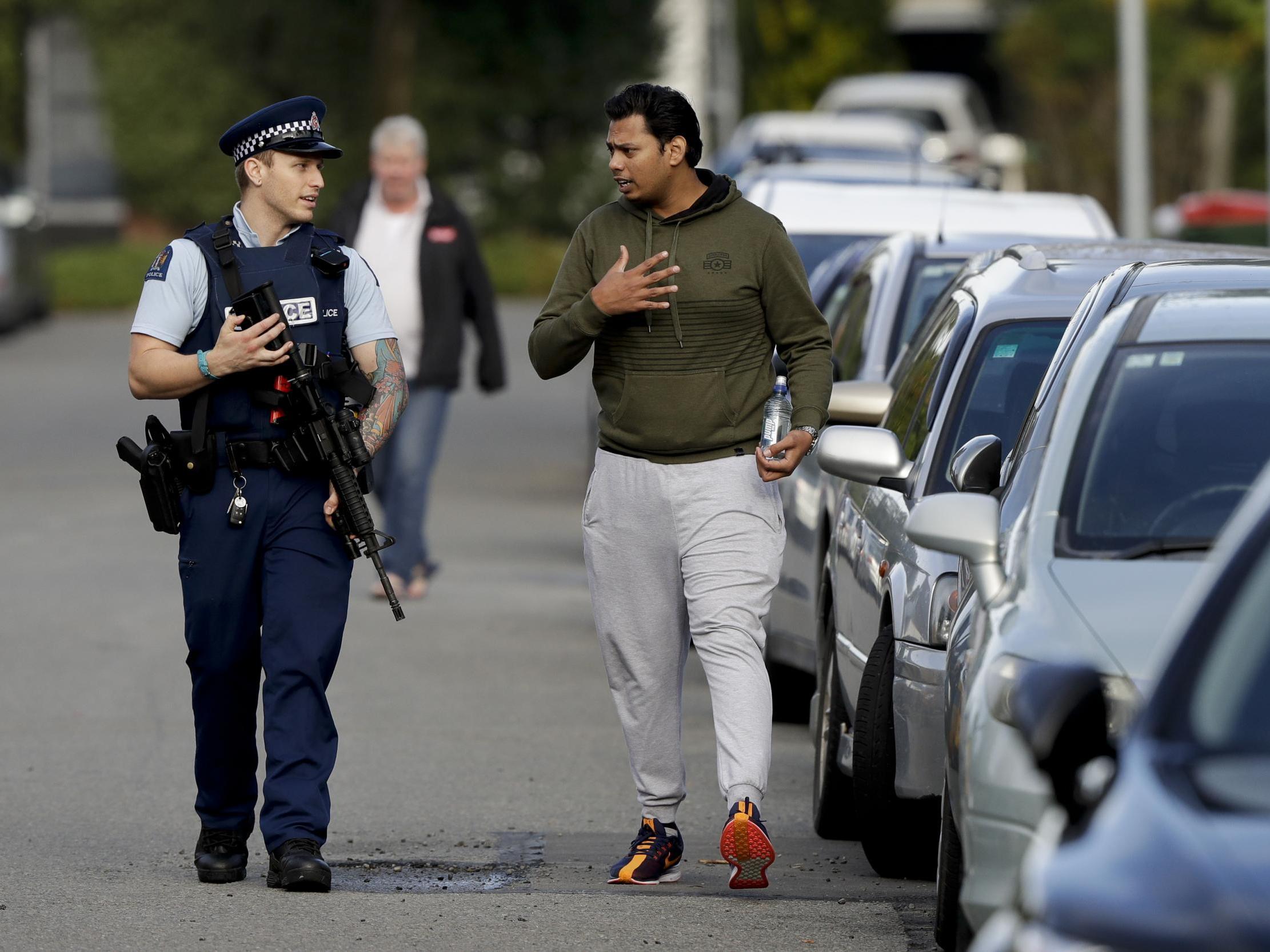 Ash Mohammed, right, talks to a police officer – his father and two brothers are missing