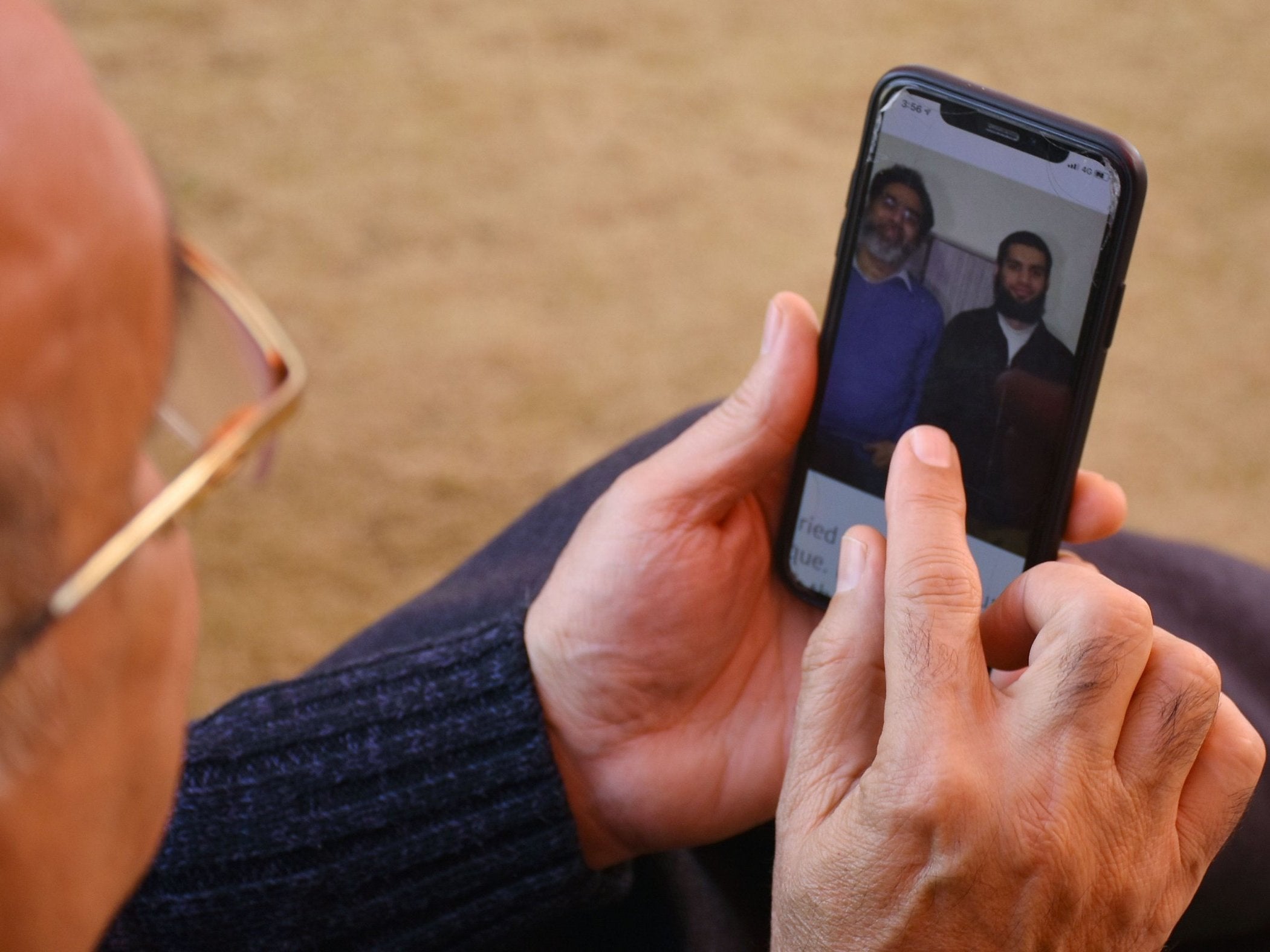 A relative looks at a picture on a mobile phone of Pakistani nationals Naeem Rashid and his son Talha Naeem (right) who died in the Christchurch shootings.