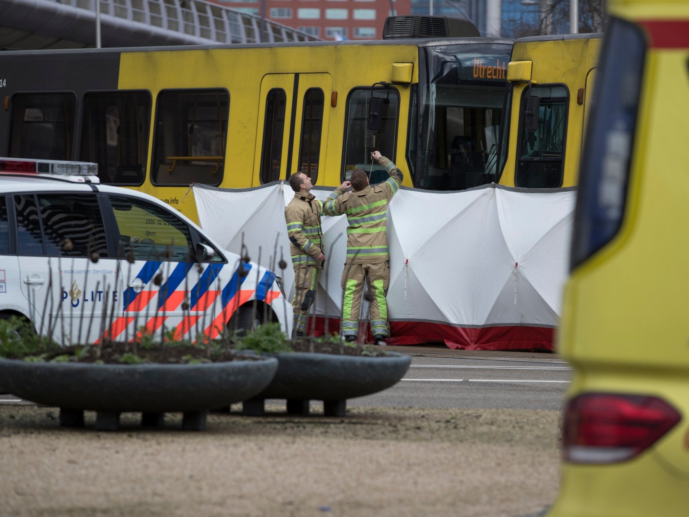 Rescue workers install a screen on the spot where a human shape was seen under a white blanket following the shooting