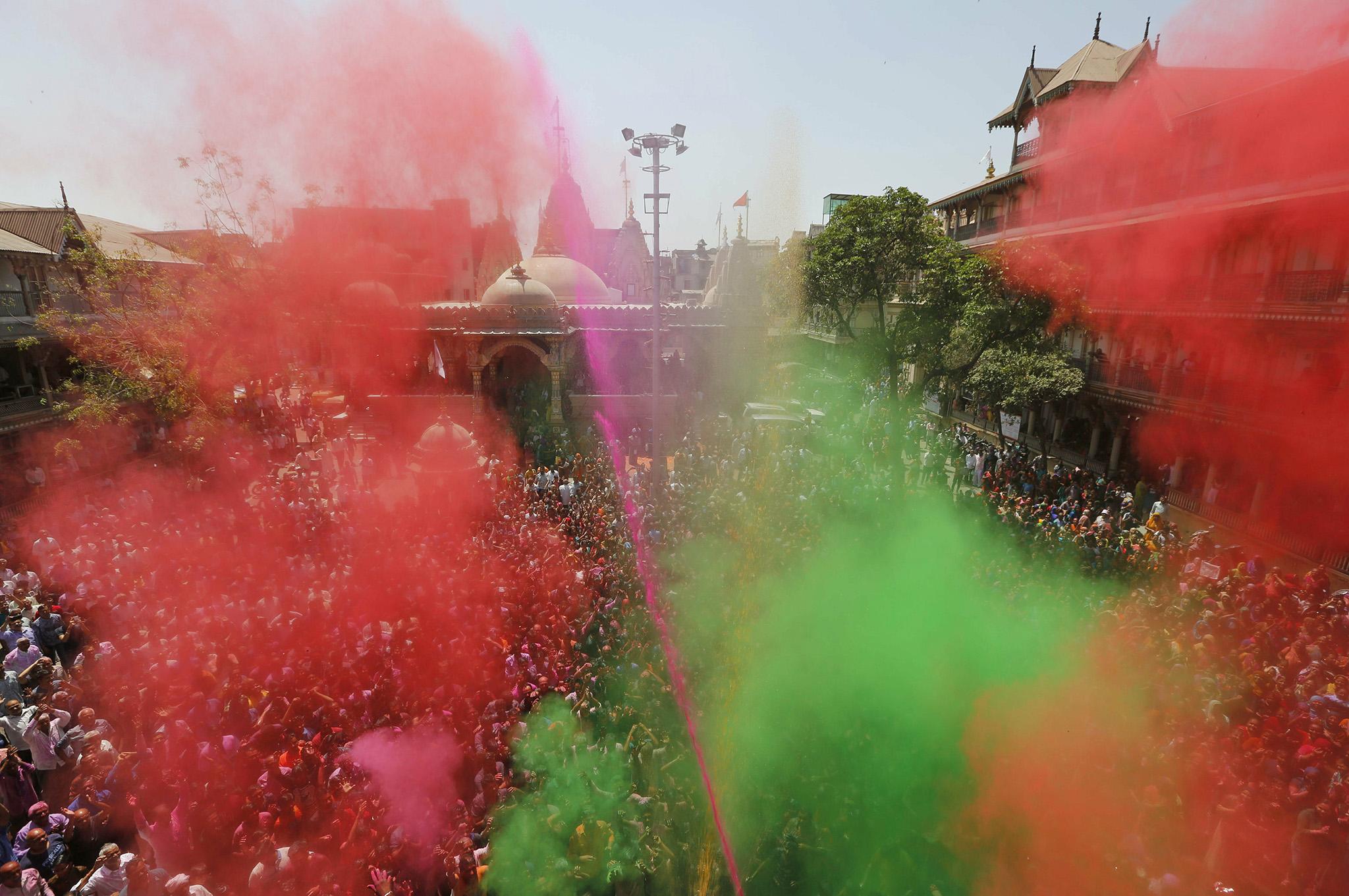 Hindu devotees are sprayed with colour by a priest during Holi celebrations in Ahmedabad, India