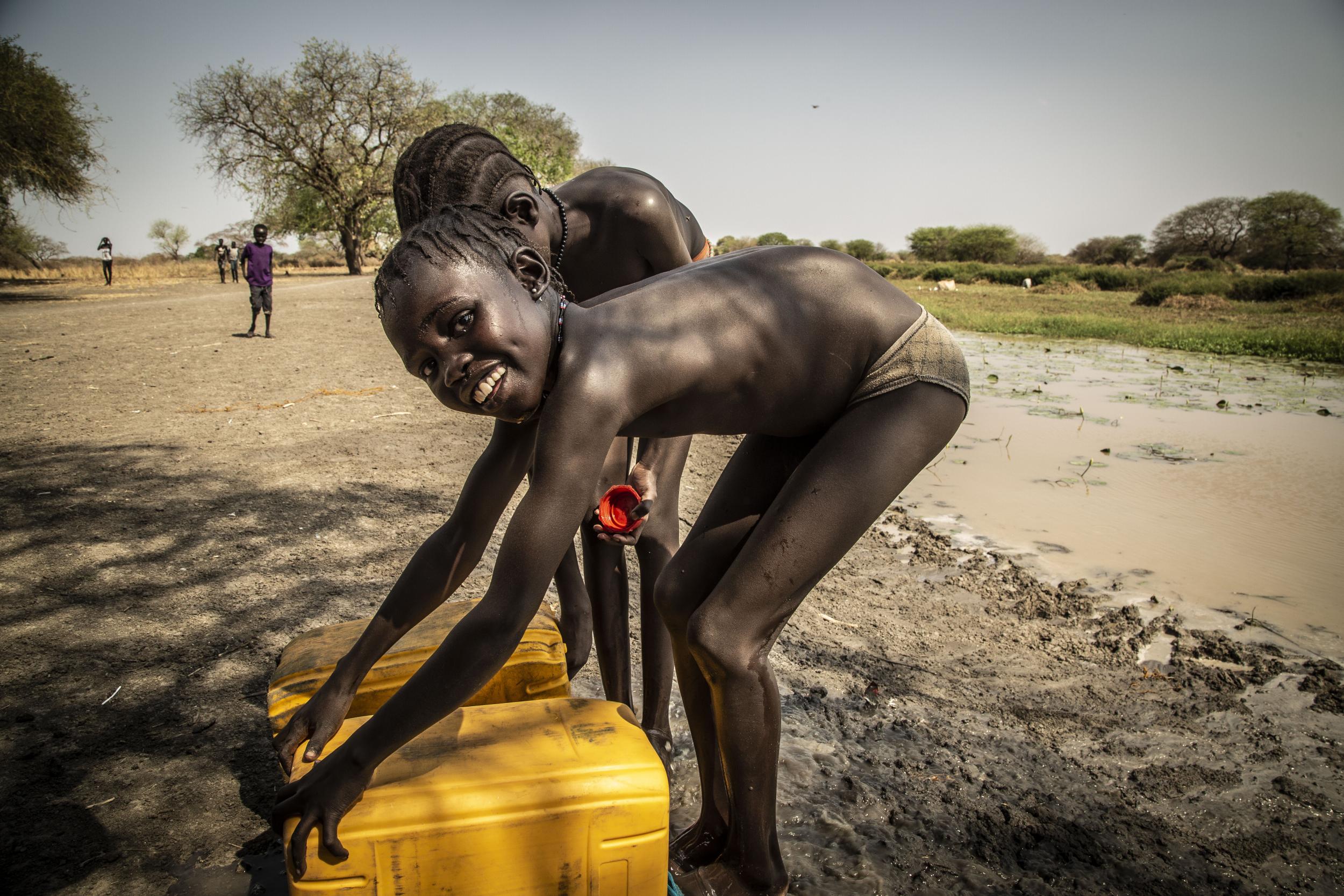 Children empty jerry cans of water in Gumuruq in remote South Sudan