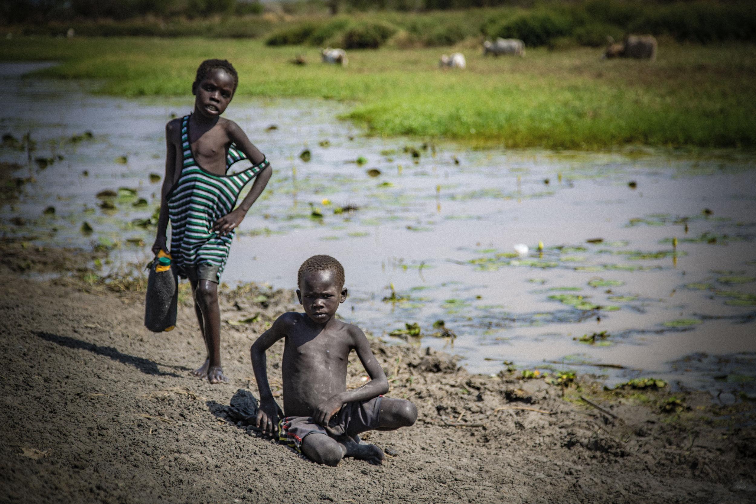 Boys on the banks of a seasonal river that is drying out a month too early due to climate change in South Sudan