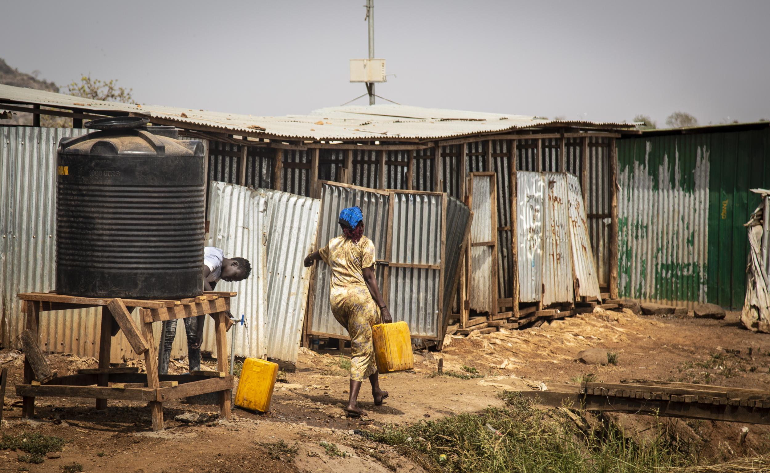 A South Sudanese woman collects water for her family at a tank in a UN-protected displacement camp in Juba