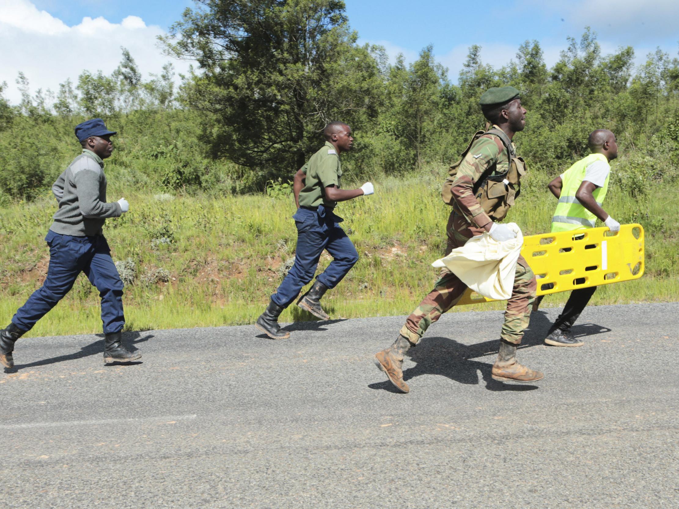 Soldiers and paramedics rush to a helicopter to carry injured survivors in Chimanimani about 600 kilometres south east of Harare, Zimbabwe, Tuesday, March, 19, 2019.