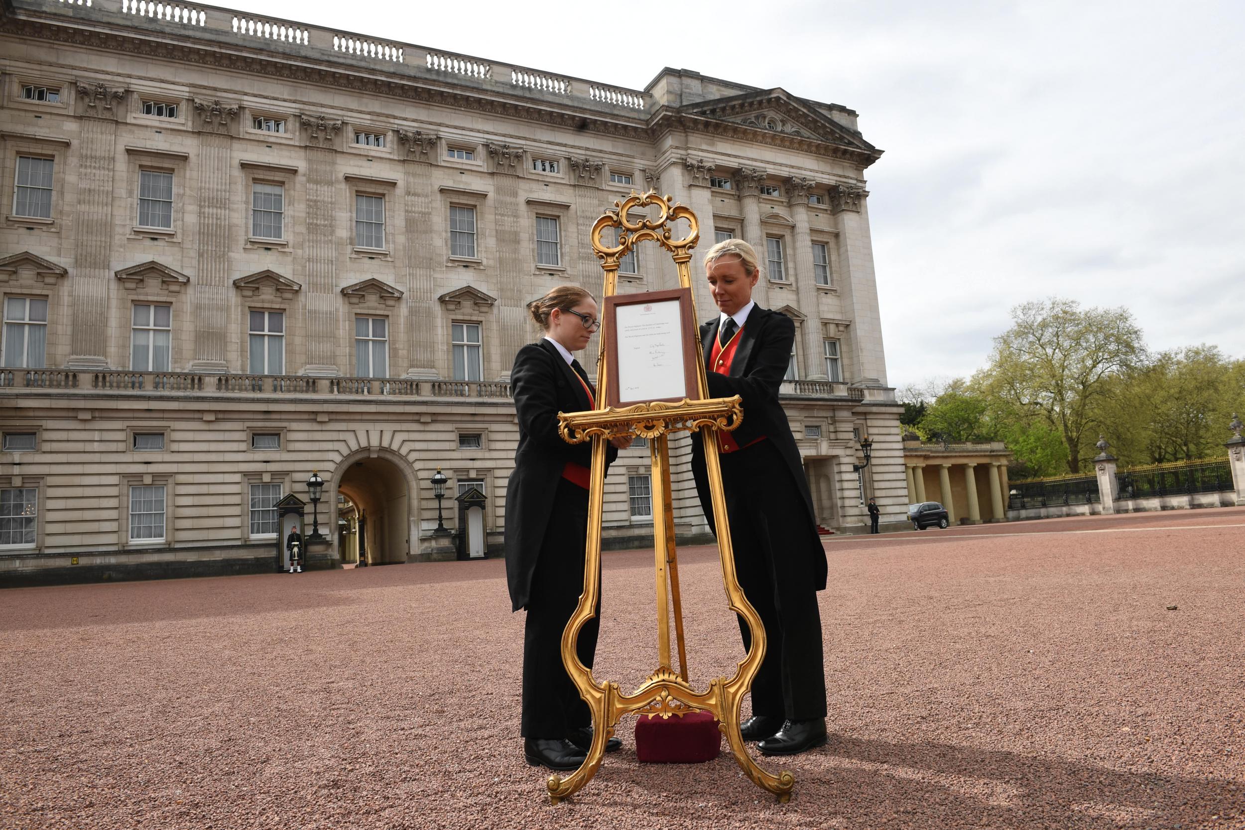 Senior footman Olivia Smith (L) and footman Heather McDonald place a notice on an easel in the forecourt of Buckingham Palace in London to formally announce the birth of a baby boy to the Duke and Duchess of Cambridge at the Lindo Wing of St Mary's Hospital on April 23, 2018 in London, England