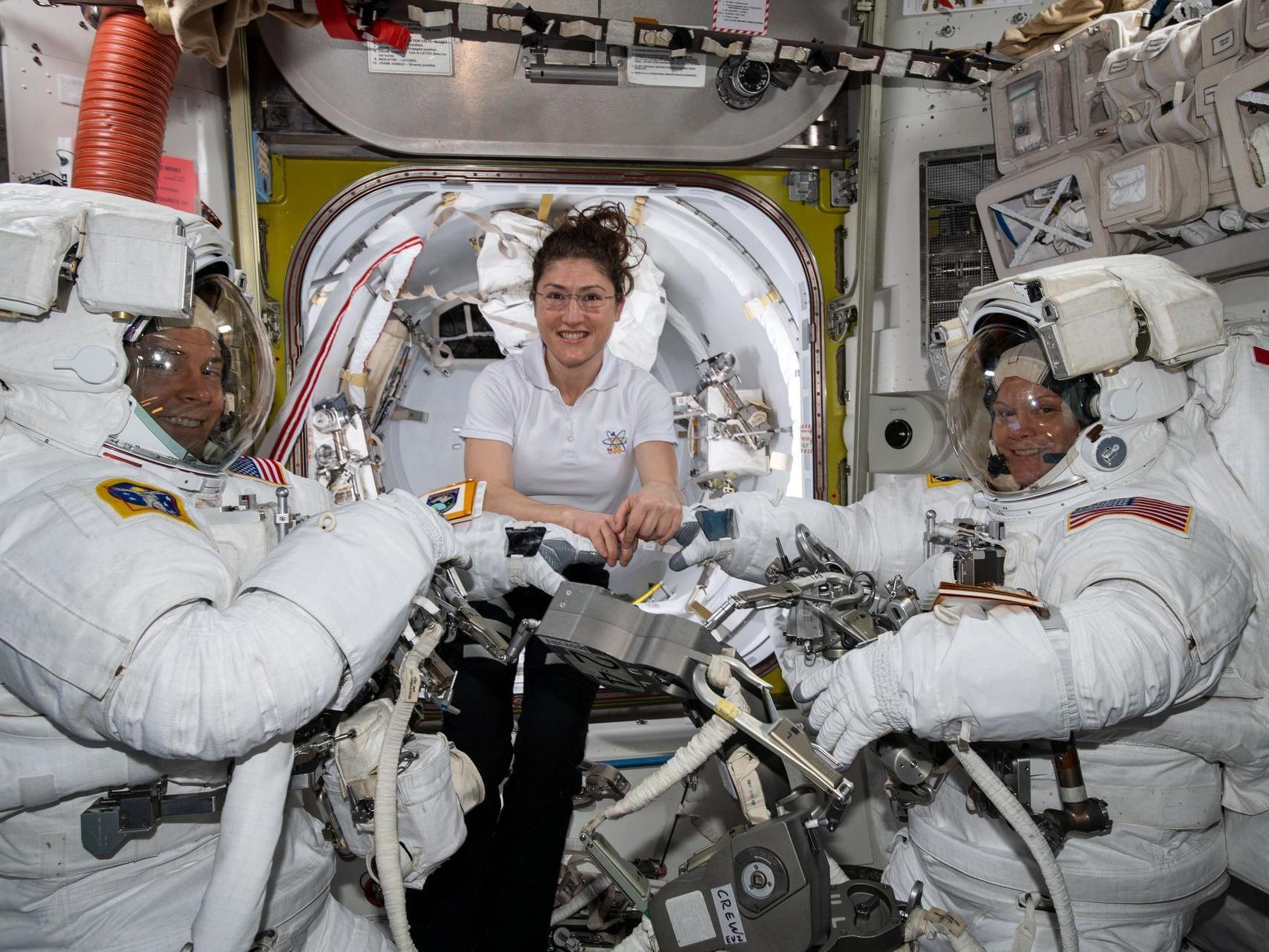 Christina Koch (centre) assists fellow astronauts Nick Hague (left) and Anne McClain in their US spacesuits shortly before they begin the first spacewalk of their careers