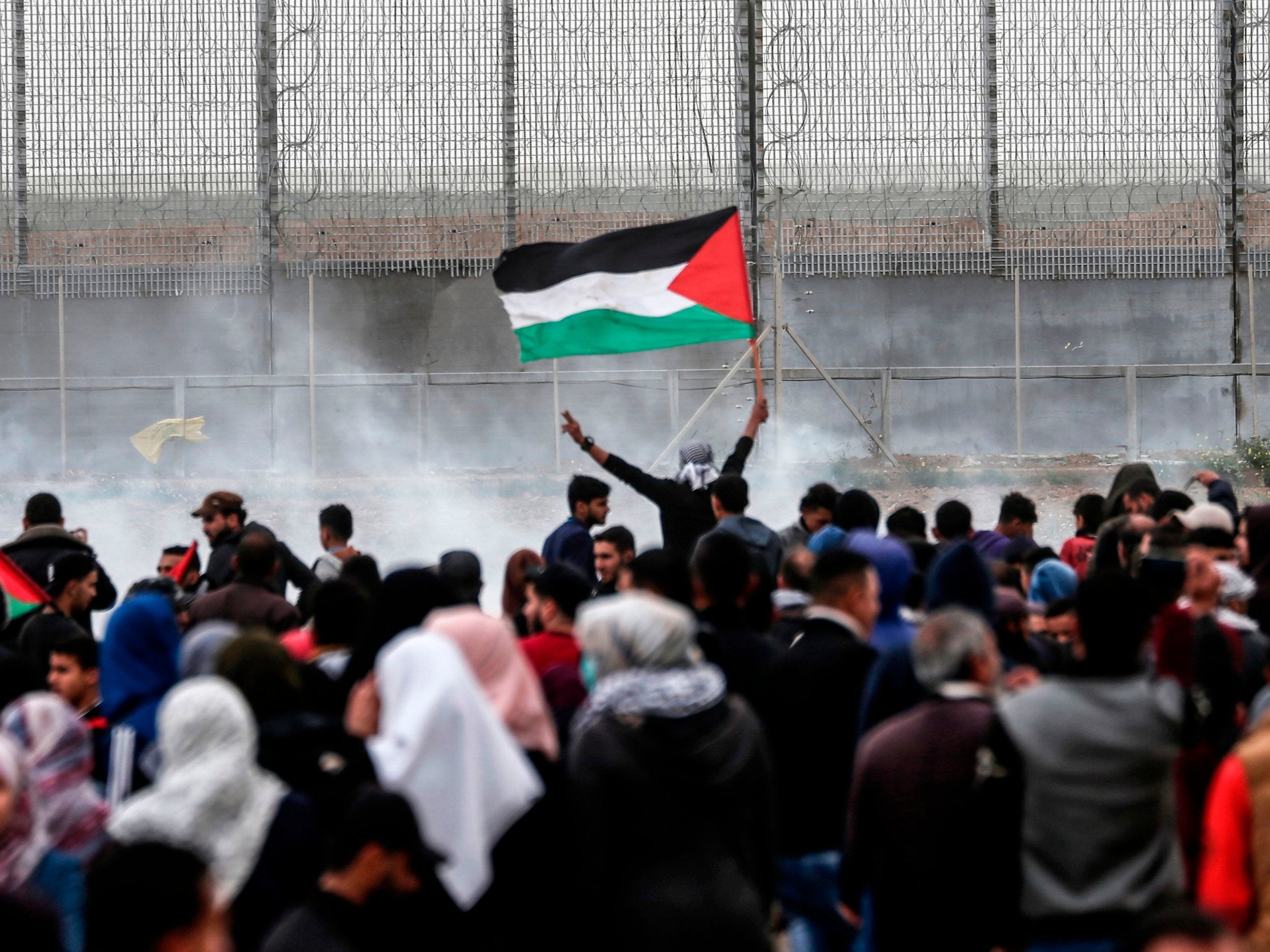 A Palestinian protester waves the national flag near the border with Israel east of Gaza City