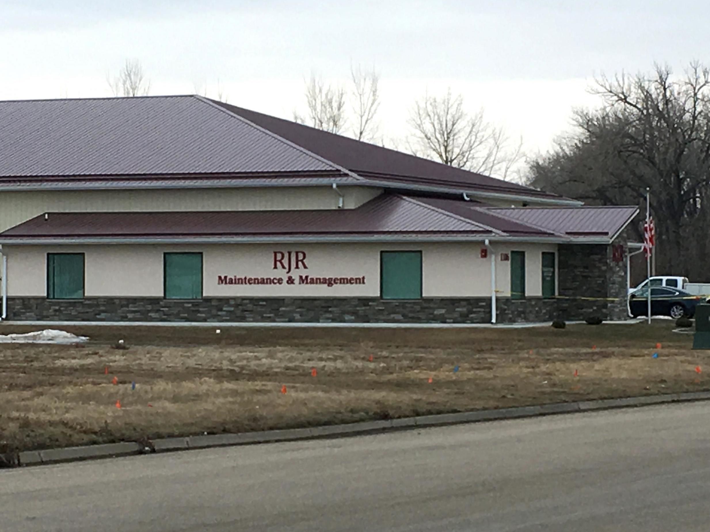 Cars are parked outside RJR Maintenance and Management in Mandan, N.D., on Monday, April 1, 2019. Police in North Dakota say "several" bodies have been found inside the business in suburban Bismarck.