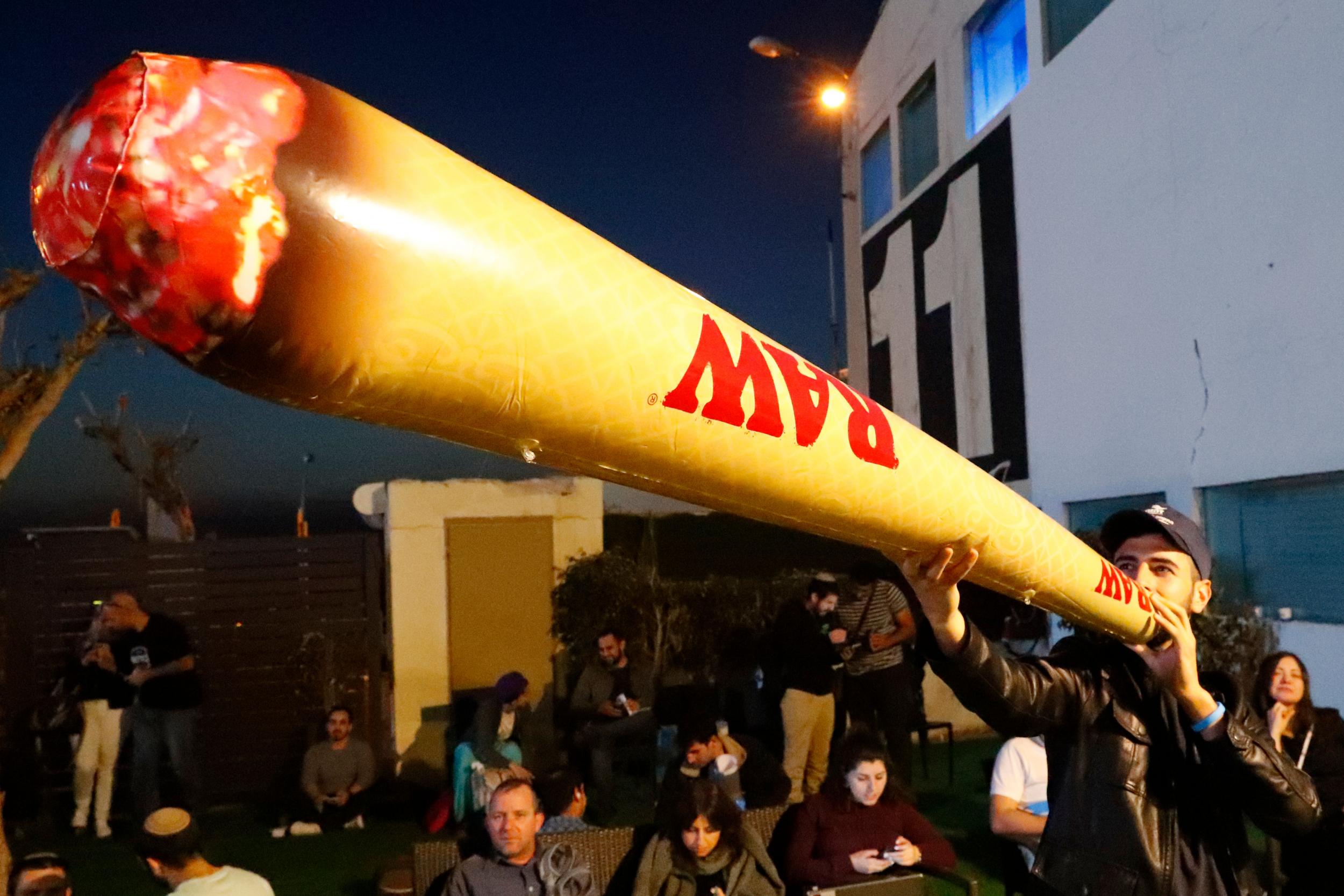 A supporter of the leader of the far-right Zehut political party Moshe Feigling smokes a fake inflatable joint during a meeting in Tel Aviv (AFP/Getty)