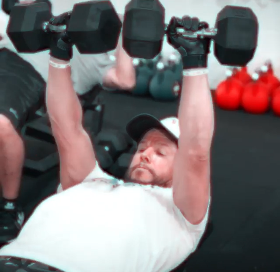 Wahlberg lifts dumbbells while lying on a gym bench