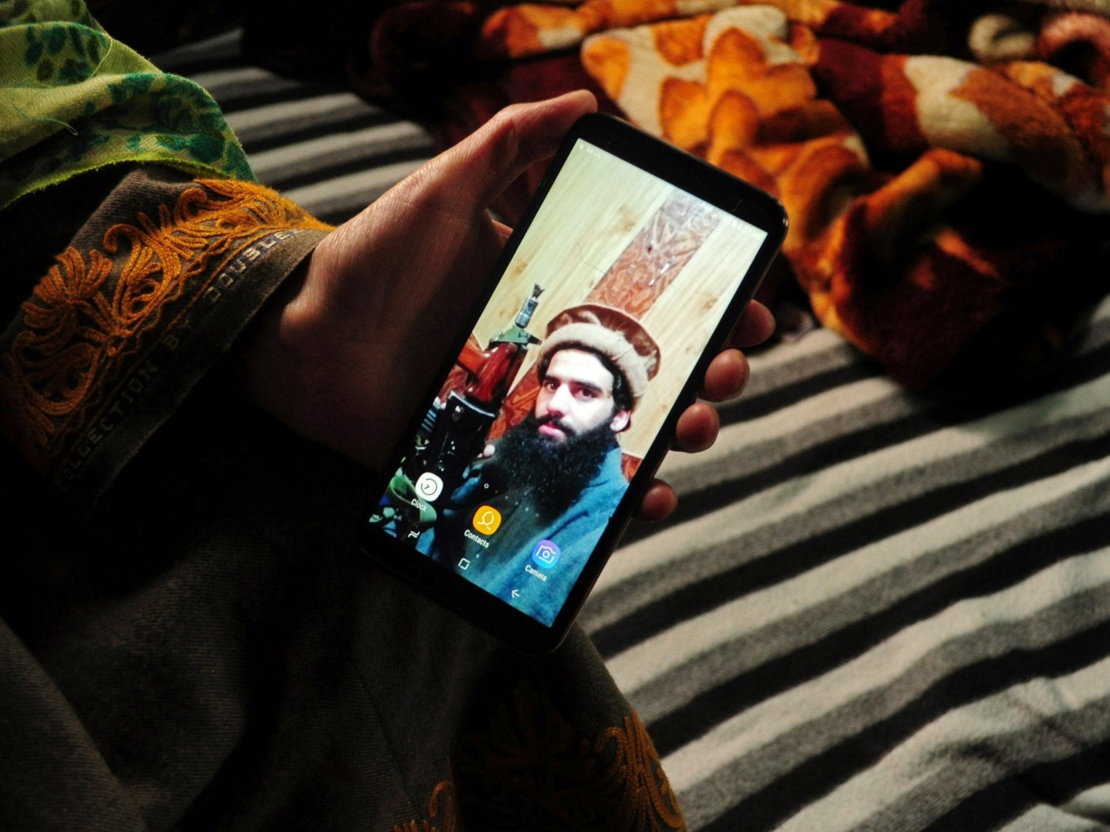 The sister of Owais Malik displays a picture of the suspected militant at her home in Kulgam, Kashmir