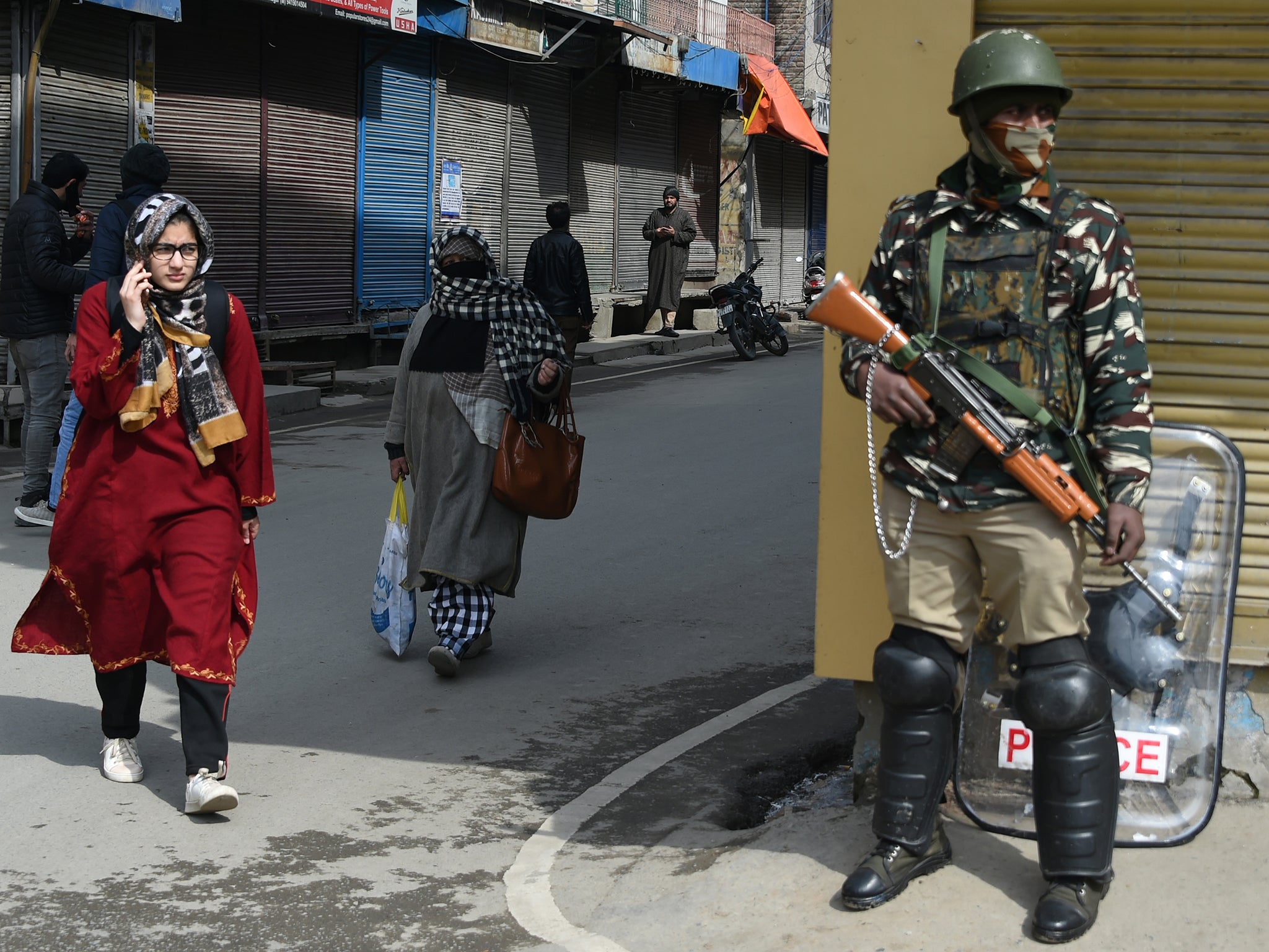 An Indian paramilitary trooper stands guard as Kashmiri residents pass during a shutdown (AFP/Getty)