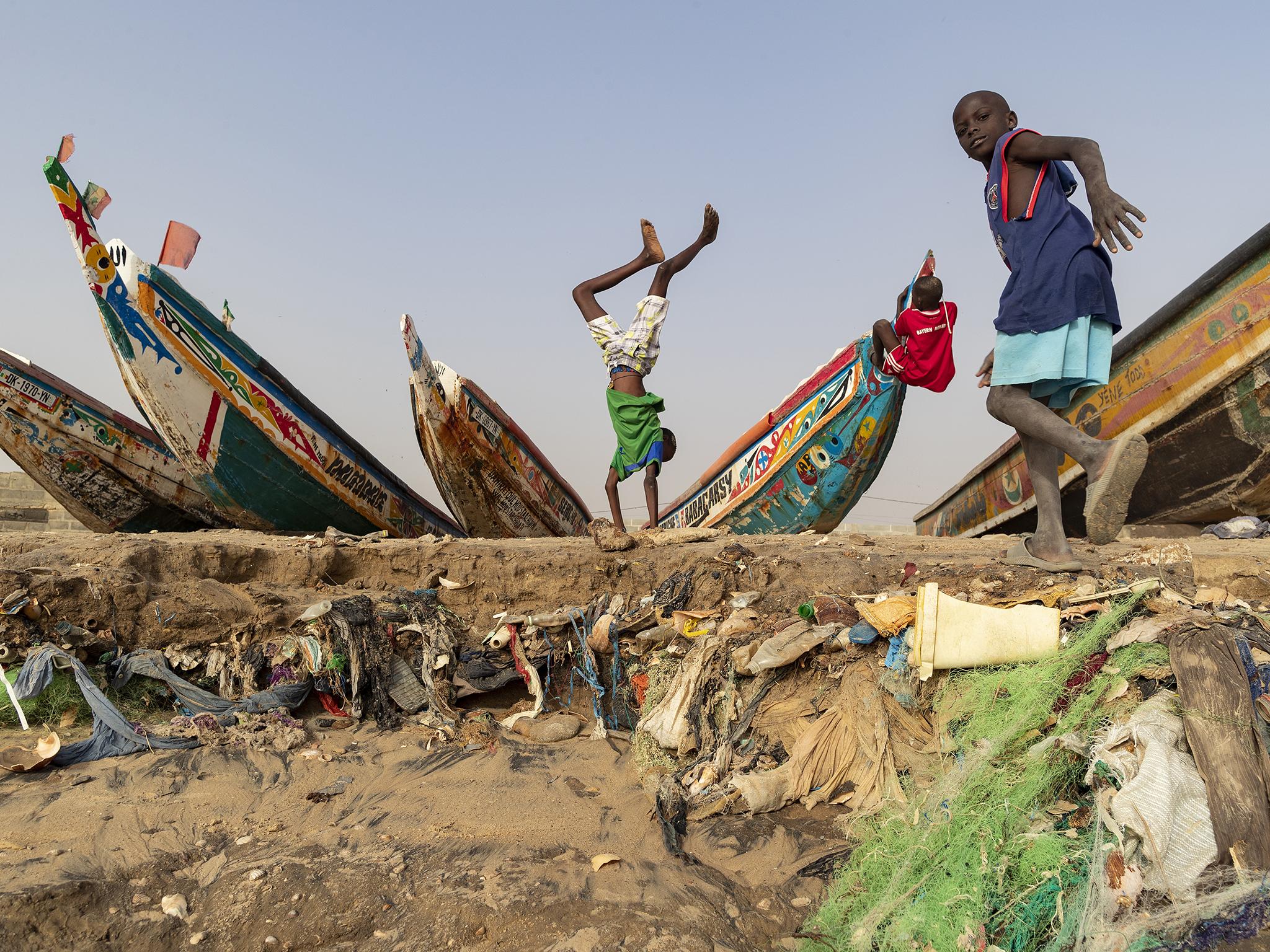 Senegalese boys play on a section of beach that has been eroded away by a big storm revealing layers of waste in the beach sand in the fishing village Yenne Todd in Senegal, 24 February 2019. Senegal is choking on plastic waste with tens of thousands of tons of it ending up in the ocean every year. A problem that is not only threatening the coastal population but also the economy. Due to a lack of comprehensive municipal waste management mechanisms communities have engaged in their own clean ups in some villages. Environmentalists urge a change of policy regarding the use of plastics is urgently needed by government.