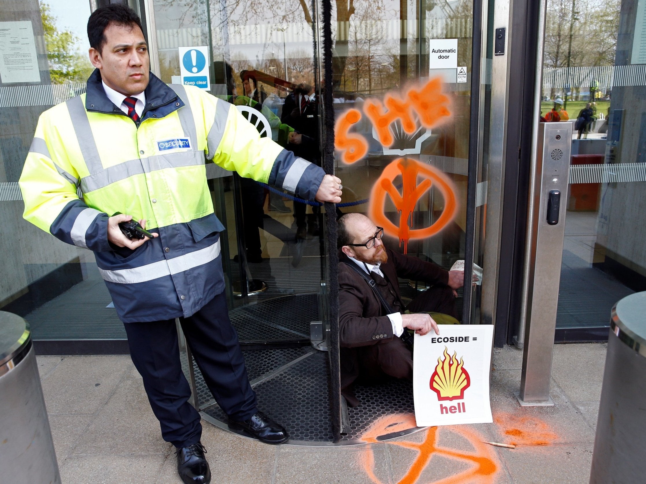 A climate change activist is seen with his hands glued to the entrance of the Shell Centre