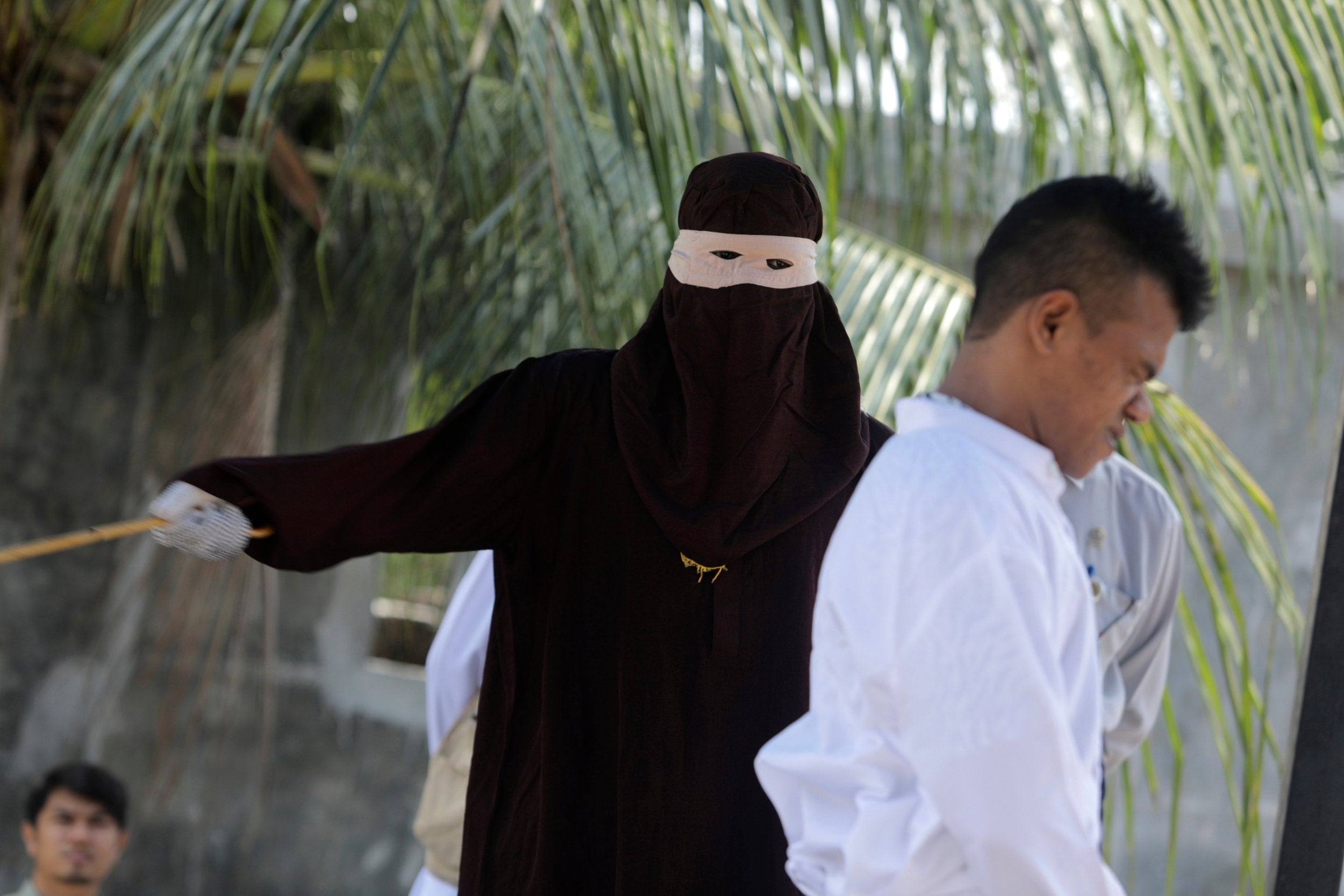 Sharia executor or 'algojo' punishes a sharia violator in public for sexual relations without marriage in Banda Aceh, Indonesia