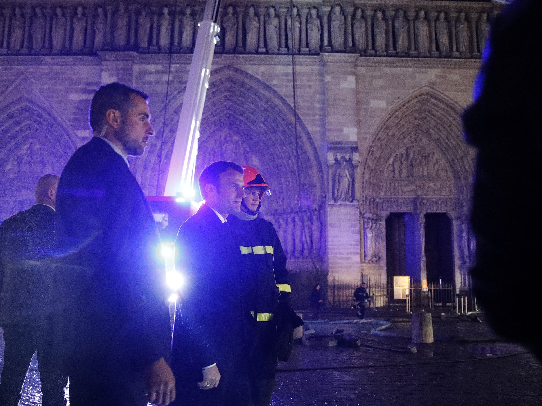 French President Emmanuel Macron speaks with firemen as they prepare to extinguish the fire.