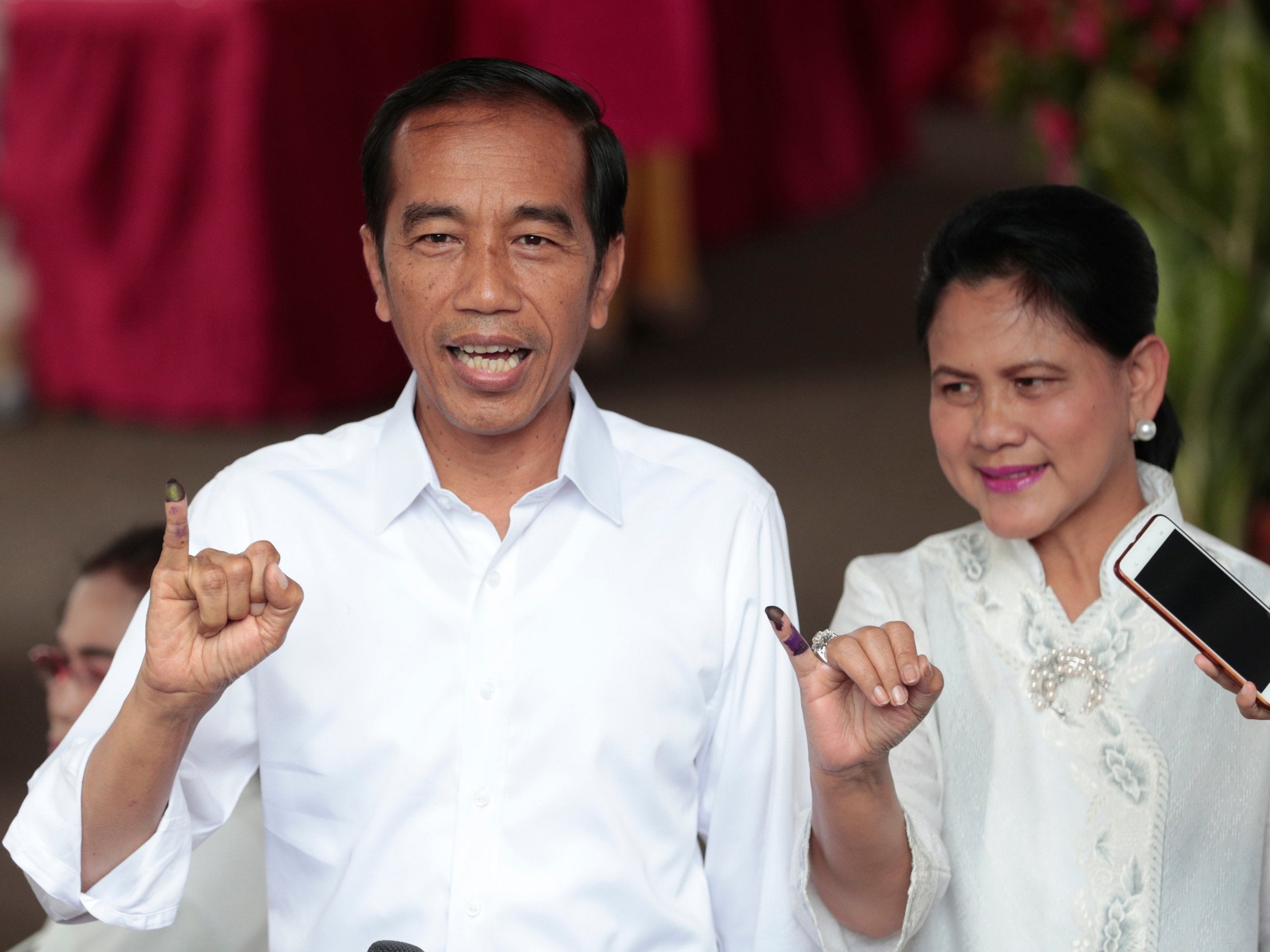 Indonesian president Joko 'Jokowi' Widodo and wife Iriana show their inked fingers after casting their ballots in the 2019 election