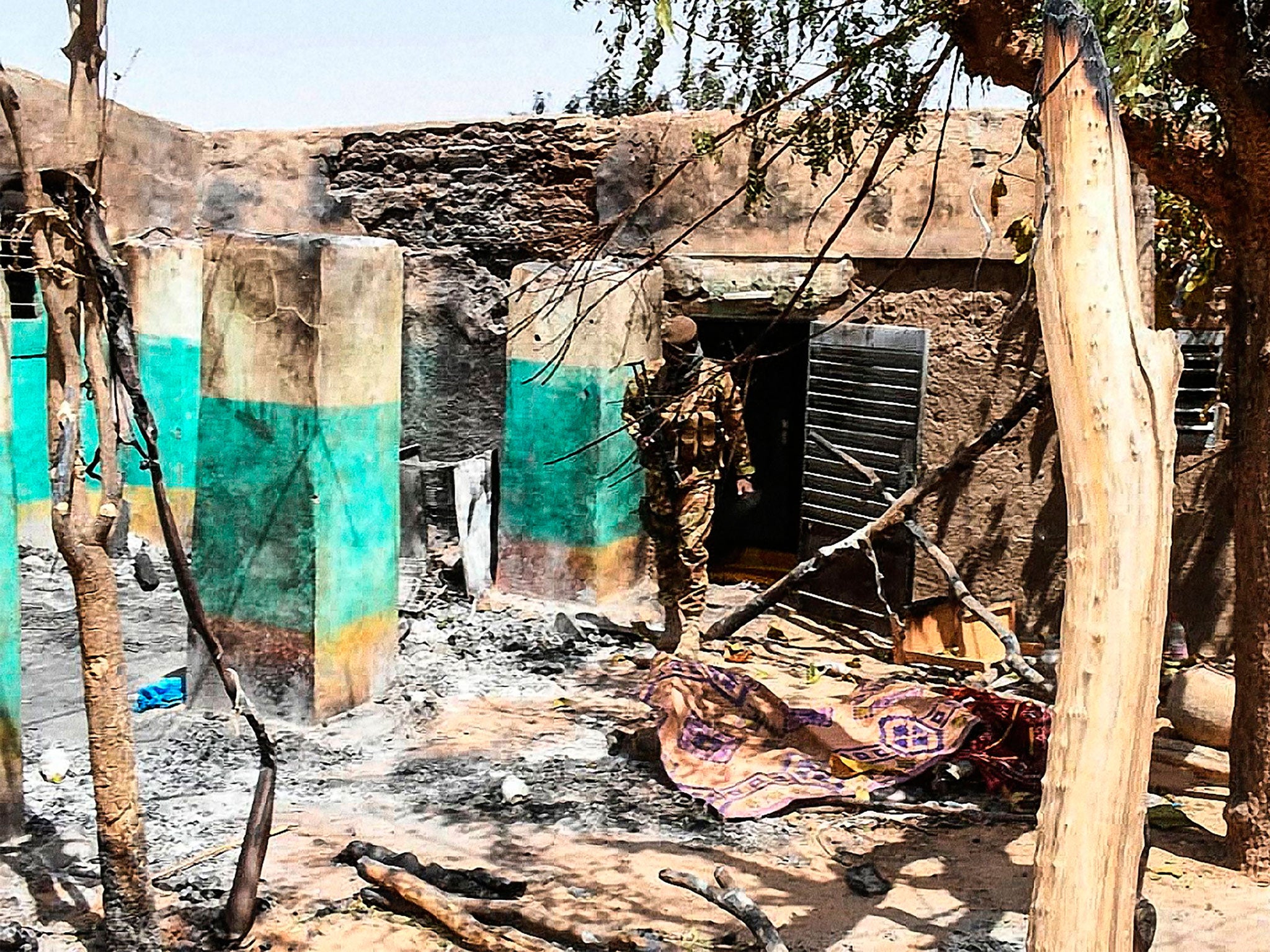 A soldier walks through debris after 160 people were killed in a massacre in the city of Ogassagou in March