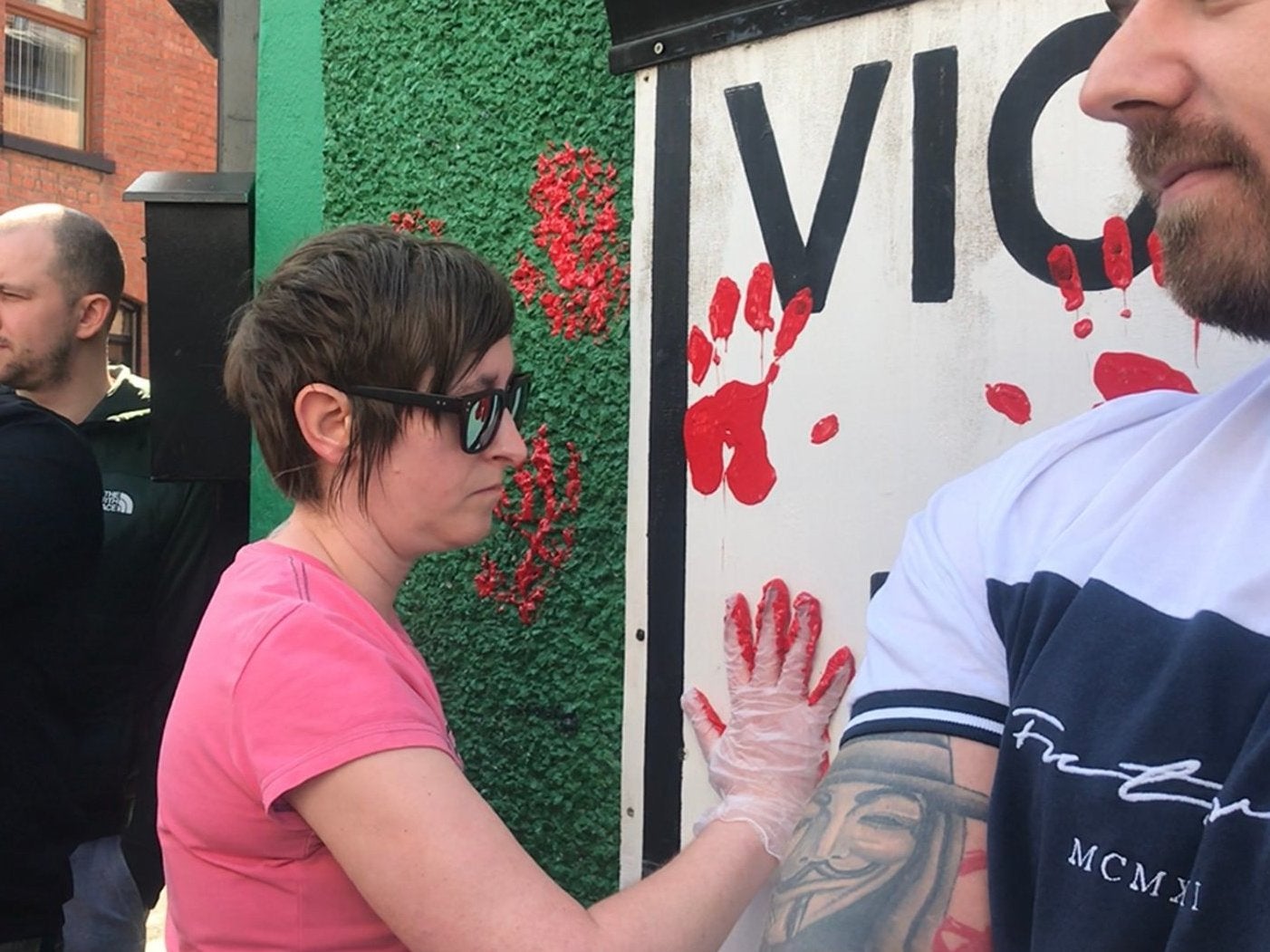 A friend of journalist Lyra McKee places a red paint handprint on the wall of a dissident republican office in Derry