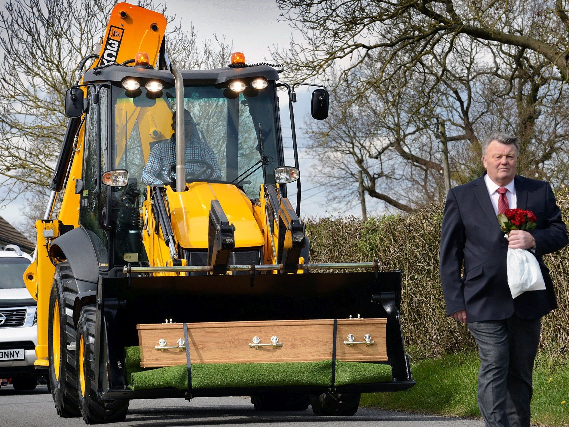 Geoffrey Durham's coffin was loaded onto the bright yellow earth mover before being driven to his final resting place.