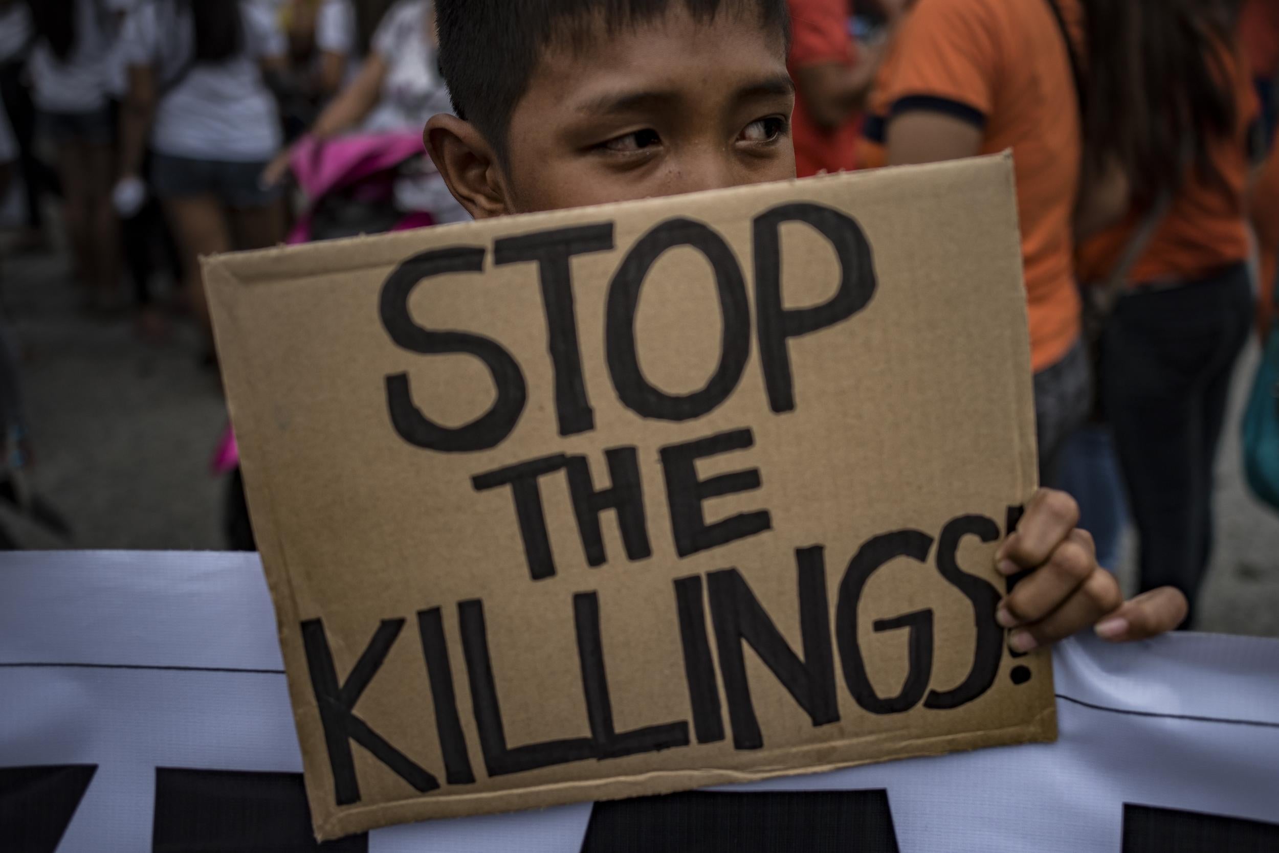 A boy holding a slogan calling to stop extrajudicial killings in Caloocan (Getty)