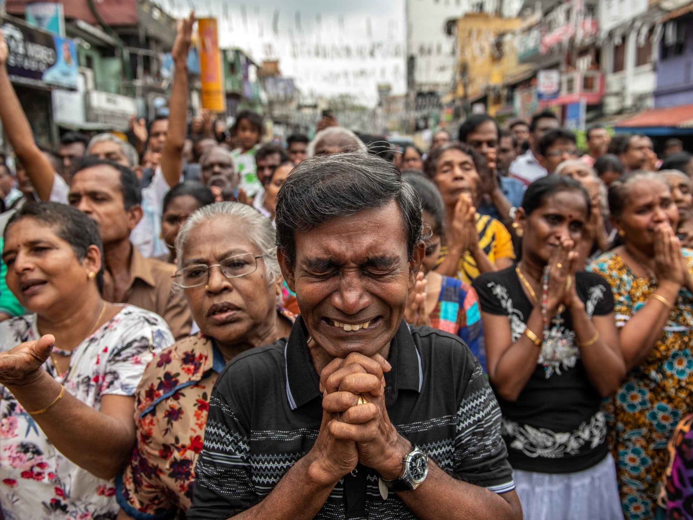 Man prays in the street near St Anthony's Shrine on Sunday, one week on from the attacks