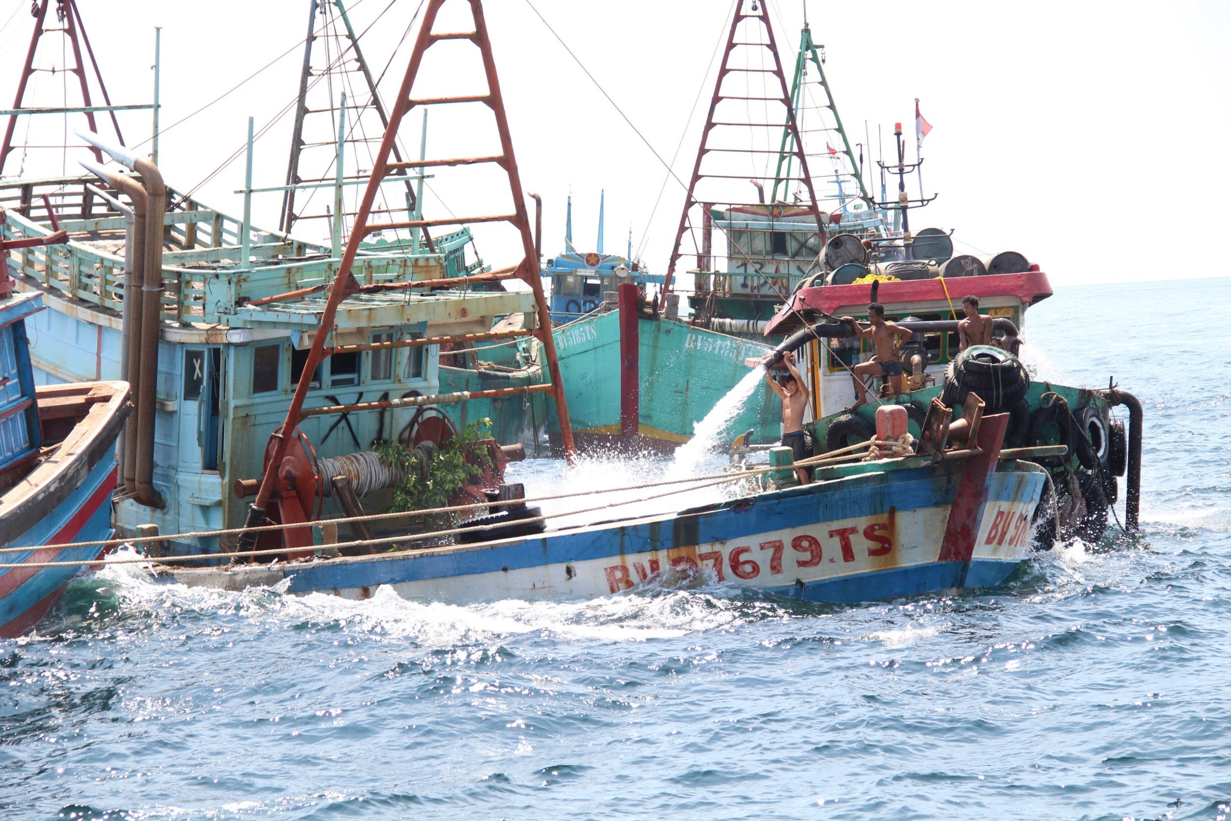 Workers flood the cargo bay of a Vietnamese-flagged boat with water as part of government's efforts to sink fishing boats caught operating illegally in Indonesian waters