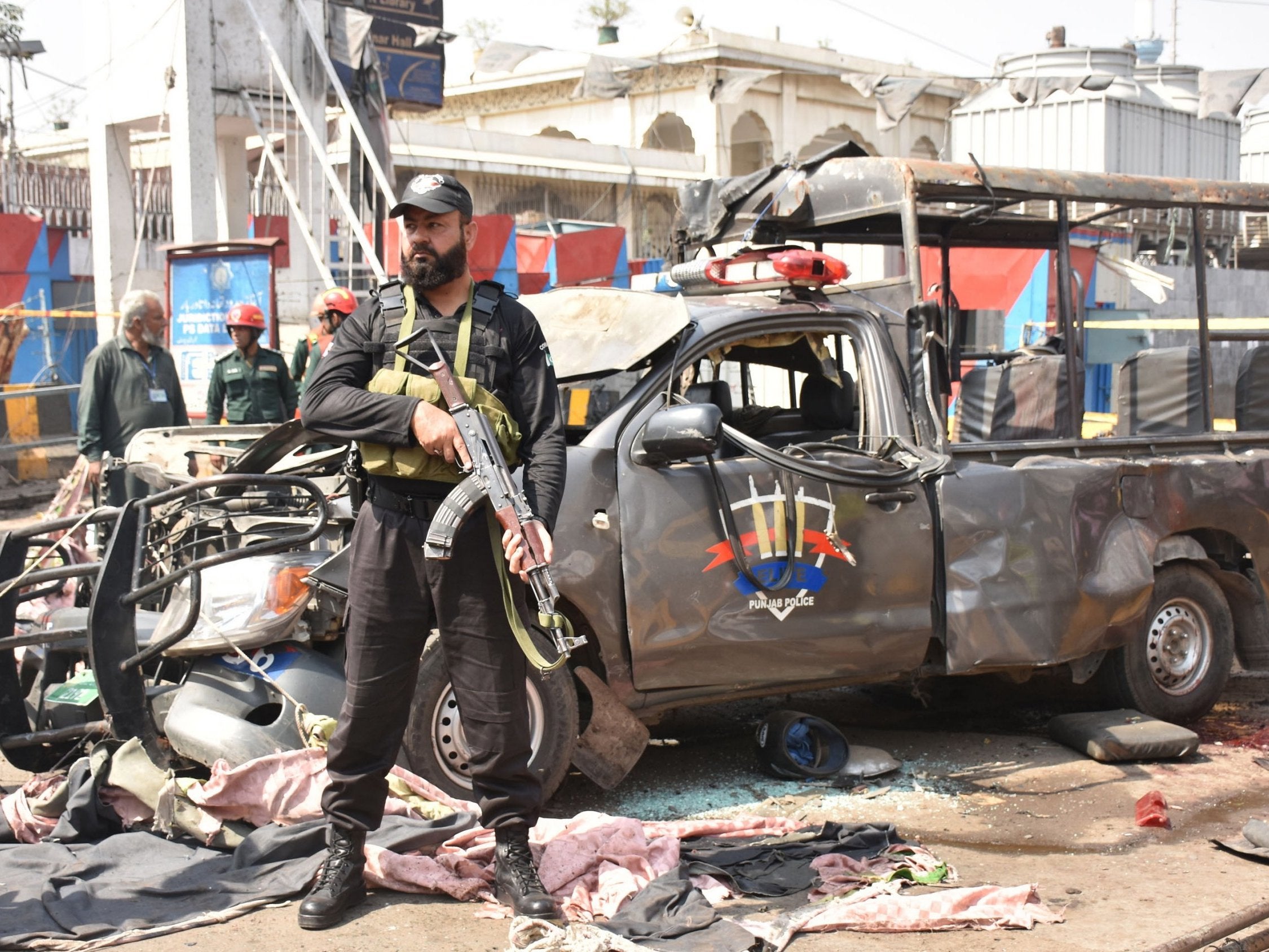 Pakistani security officials inspect the scene of a suicide bomb attack that targeted a Police vehicle outside the Data Darbar shrine in Lahore