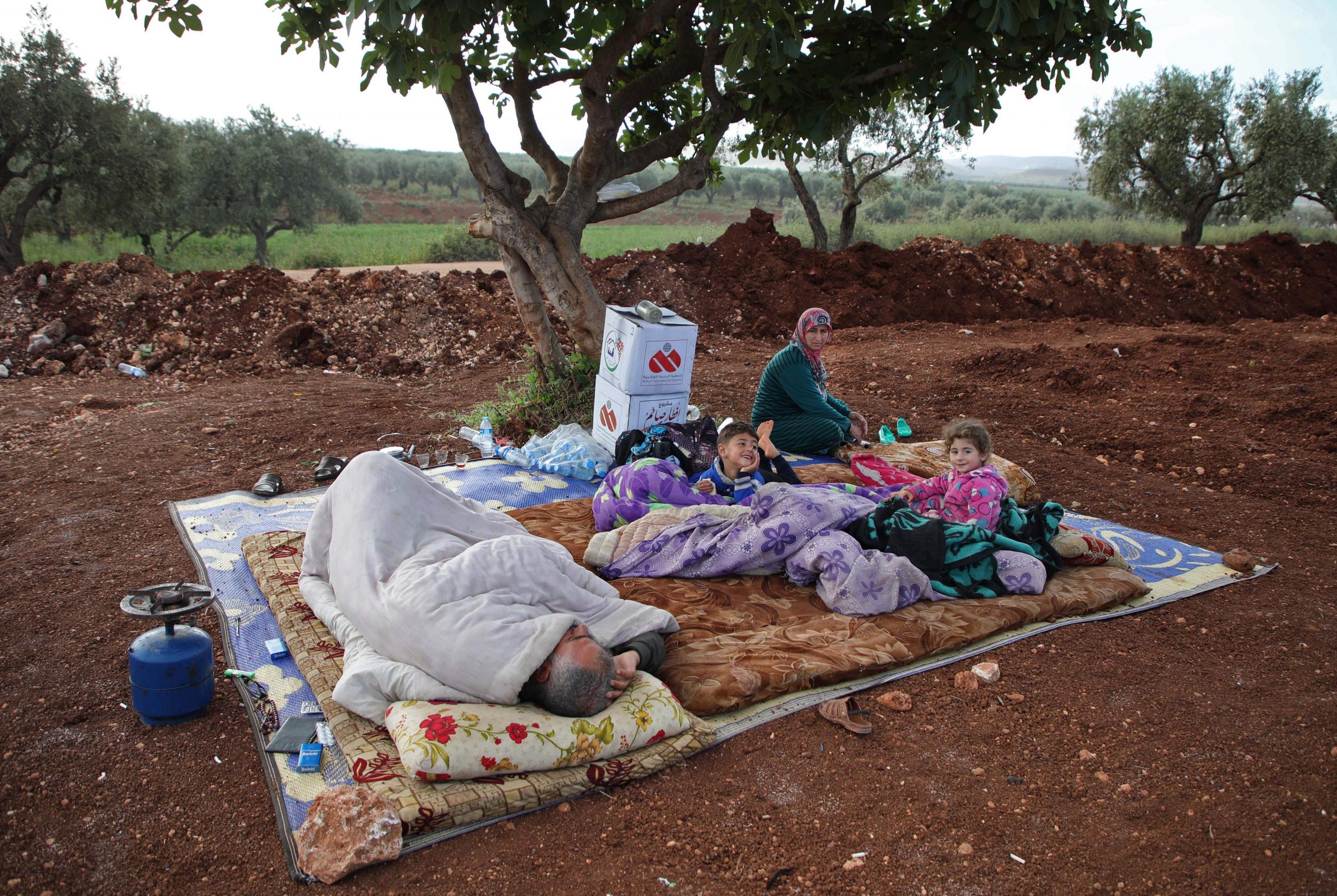 Syrians in a field near a camp for displaced people in the village of Atme, in the jihadist-held northern Idlib province on 8 May (Aaref Watad/AFP/Getty)