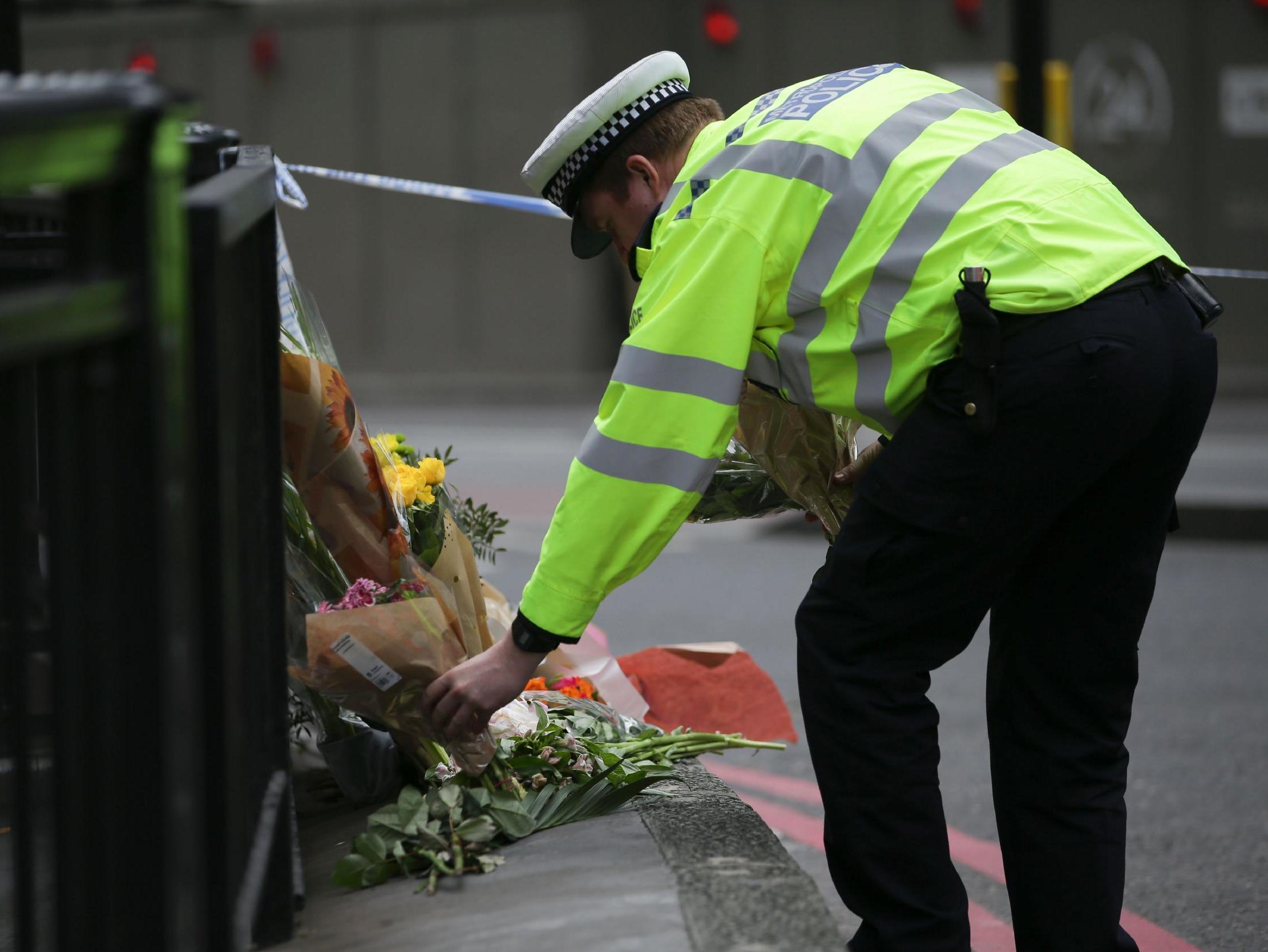 A police officer lays flowers at a police cordon on London Bridge following the terror attack on 3 June 2017.