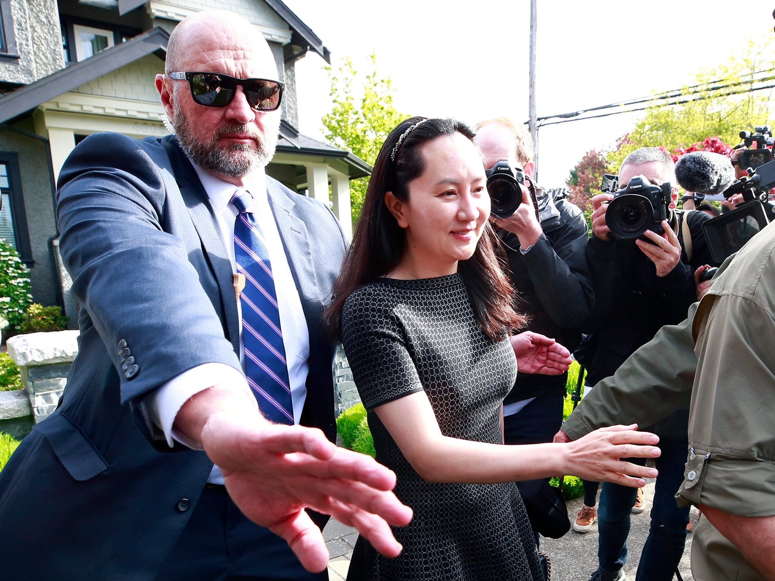 Meng Wanzhou is escorted by security as she leaves her home in Vancouver (Getty)