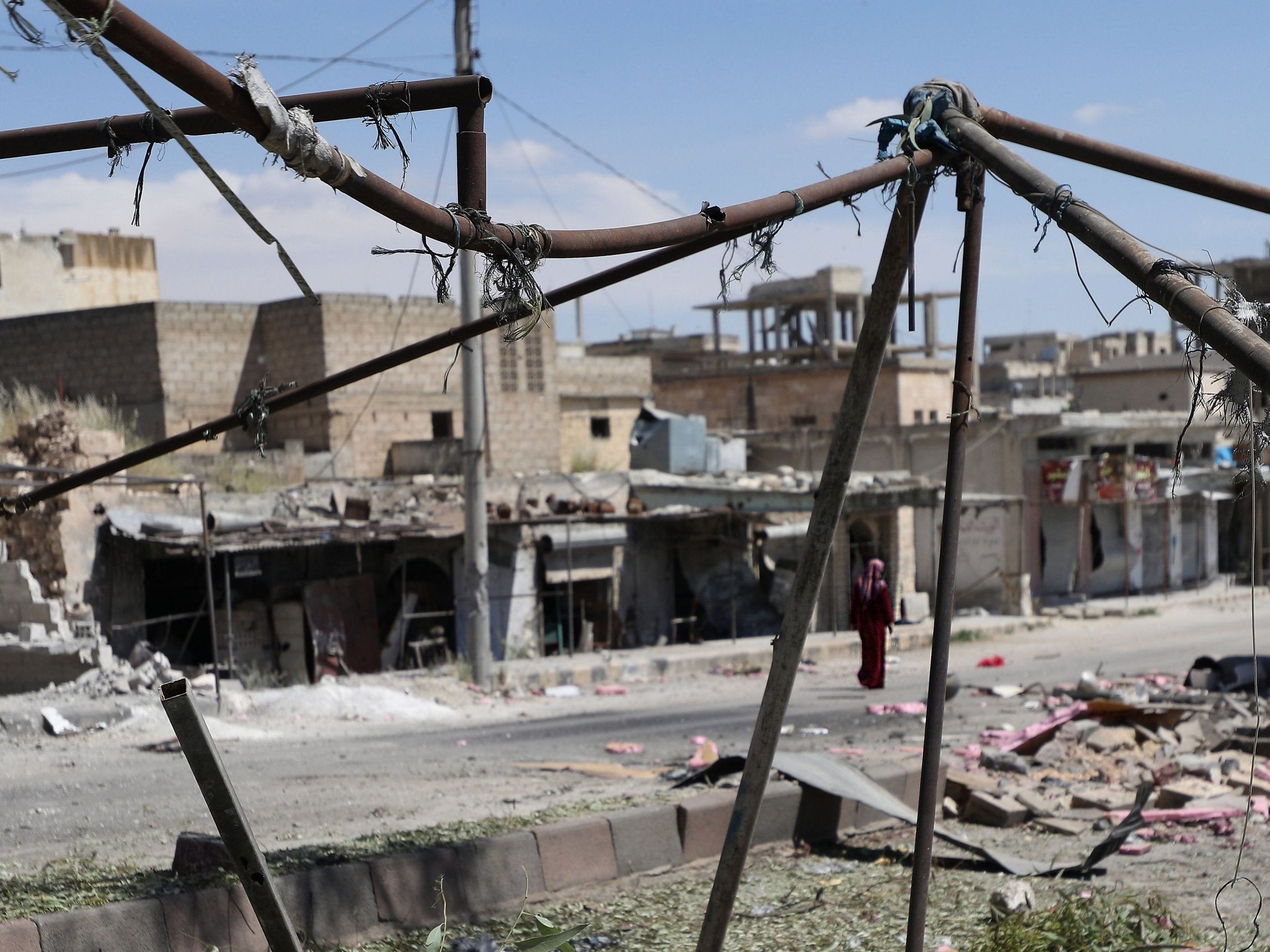 A woman walks along buildings damaged during reported shelling by government forces on the town of Khan Sheikhun in the southern countryside of the rebel-held Idlib province