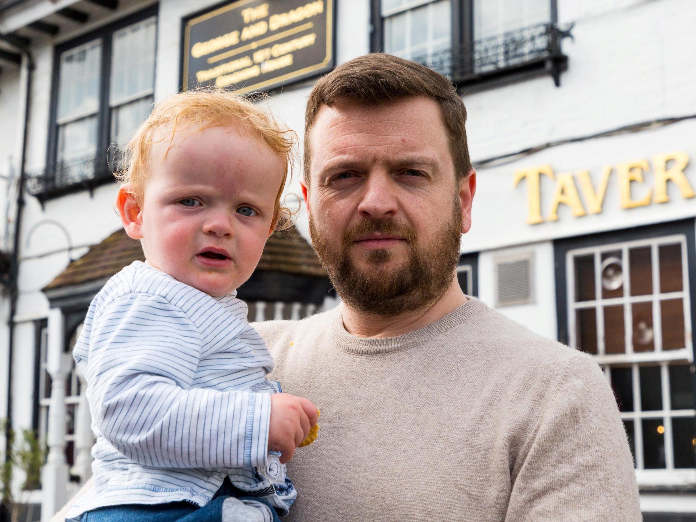 Pub landlord Patrick Tranter at his George and Dragon pub in Westerham, Kent, with his one-year-old son