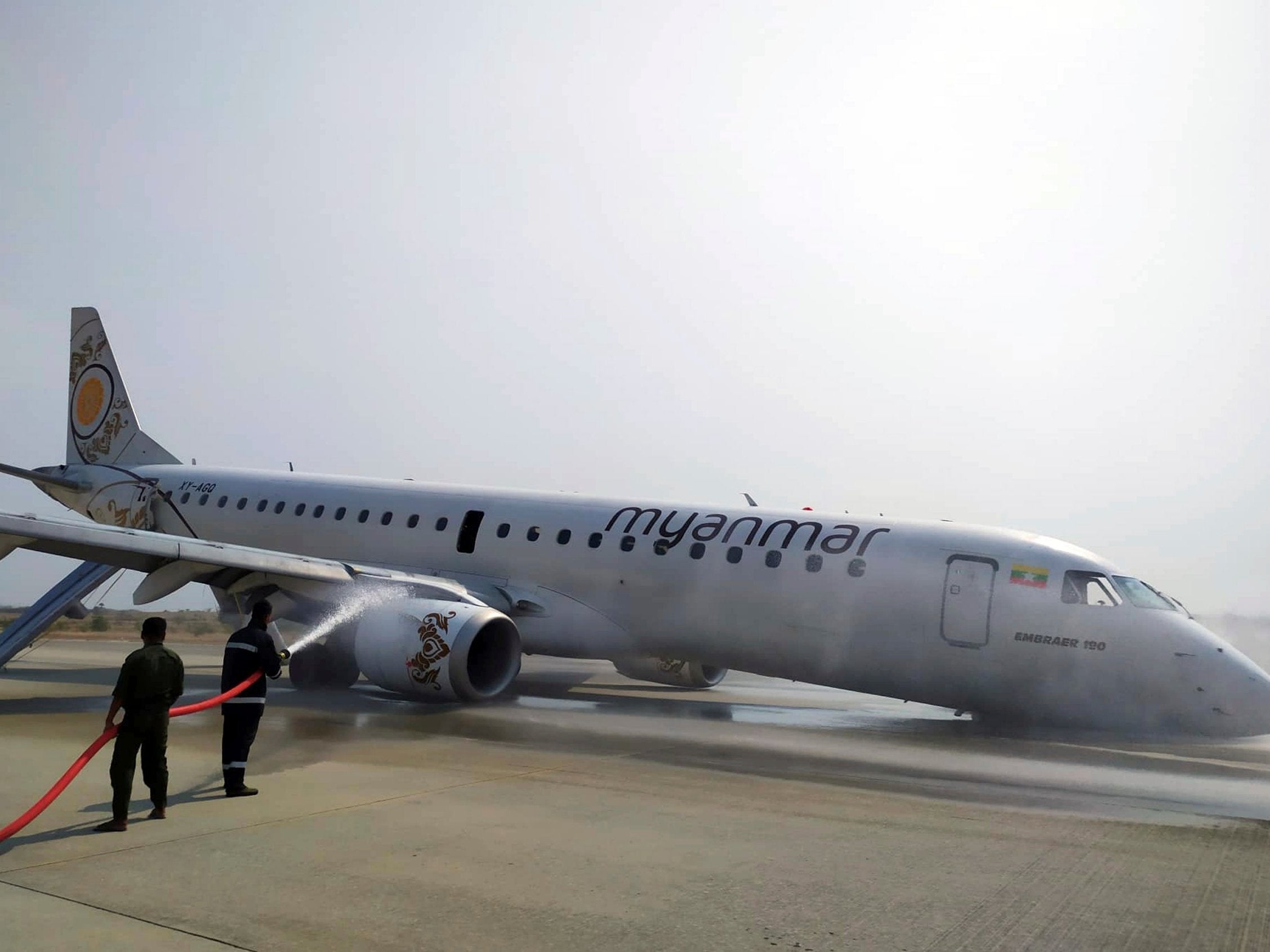 Firefighters hose down the plane after the emergency landing at Mandalay international airport