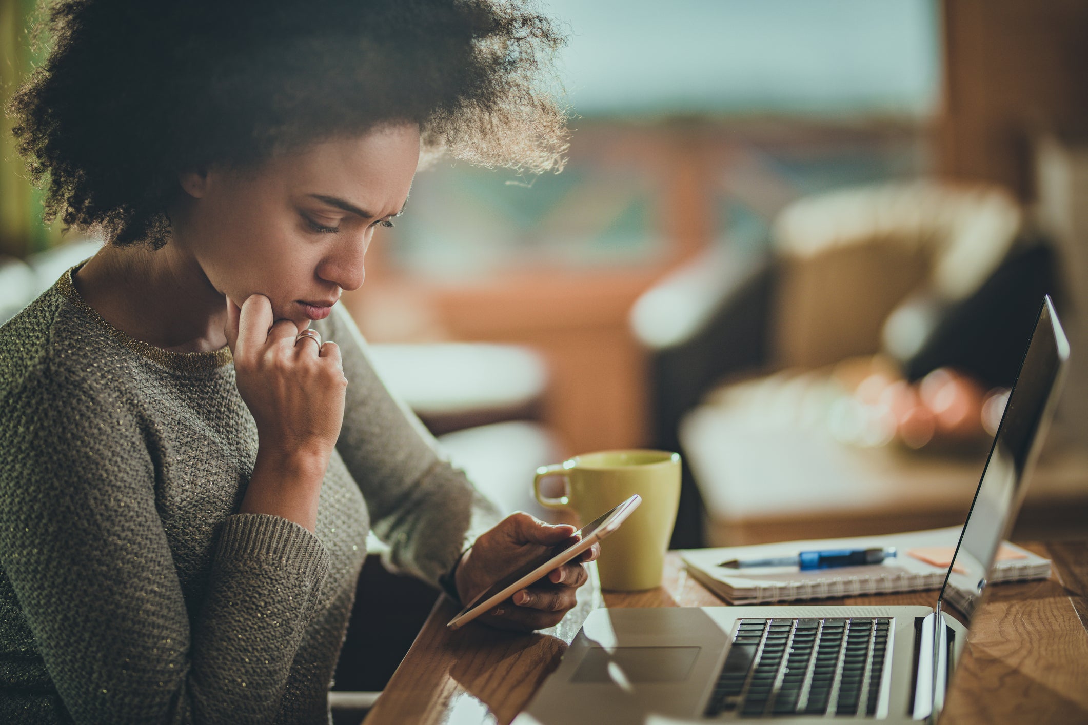 Woman using mobile phone while working at home.