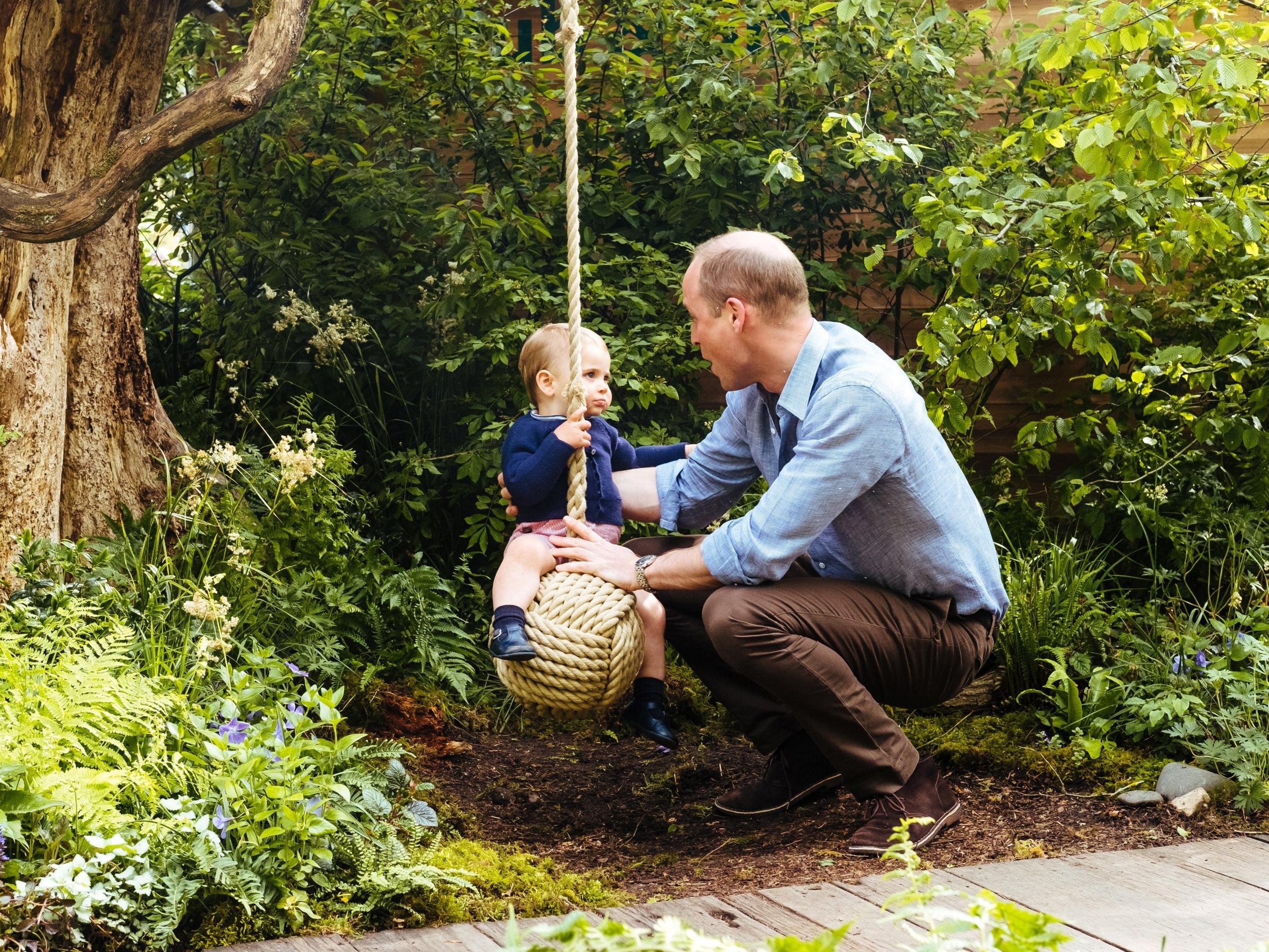 Prince William holds his youngest son as he swings on a rope