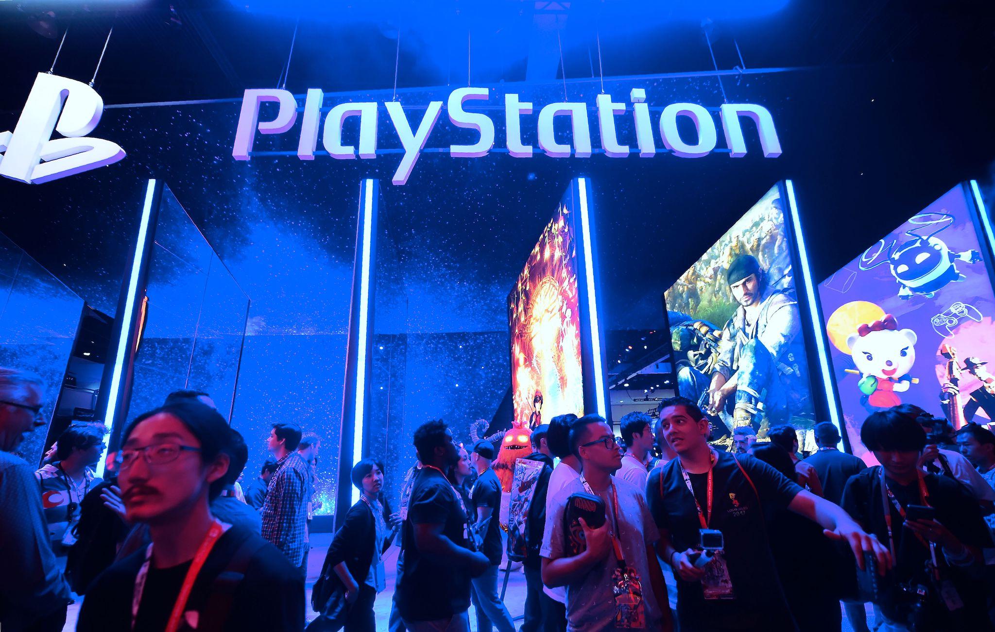 People wander in front of the Playstation posters at the 24th Electronic Expo, or E3 2018, in Los Angeles