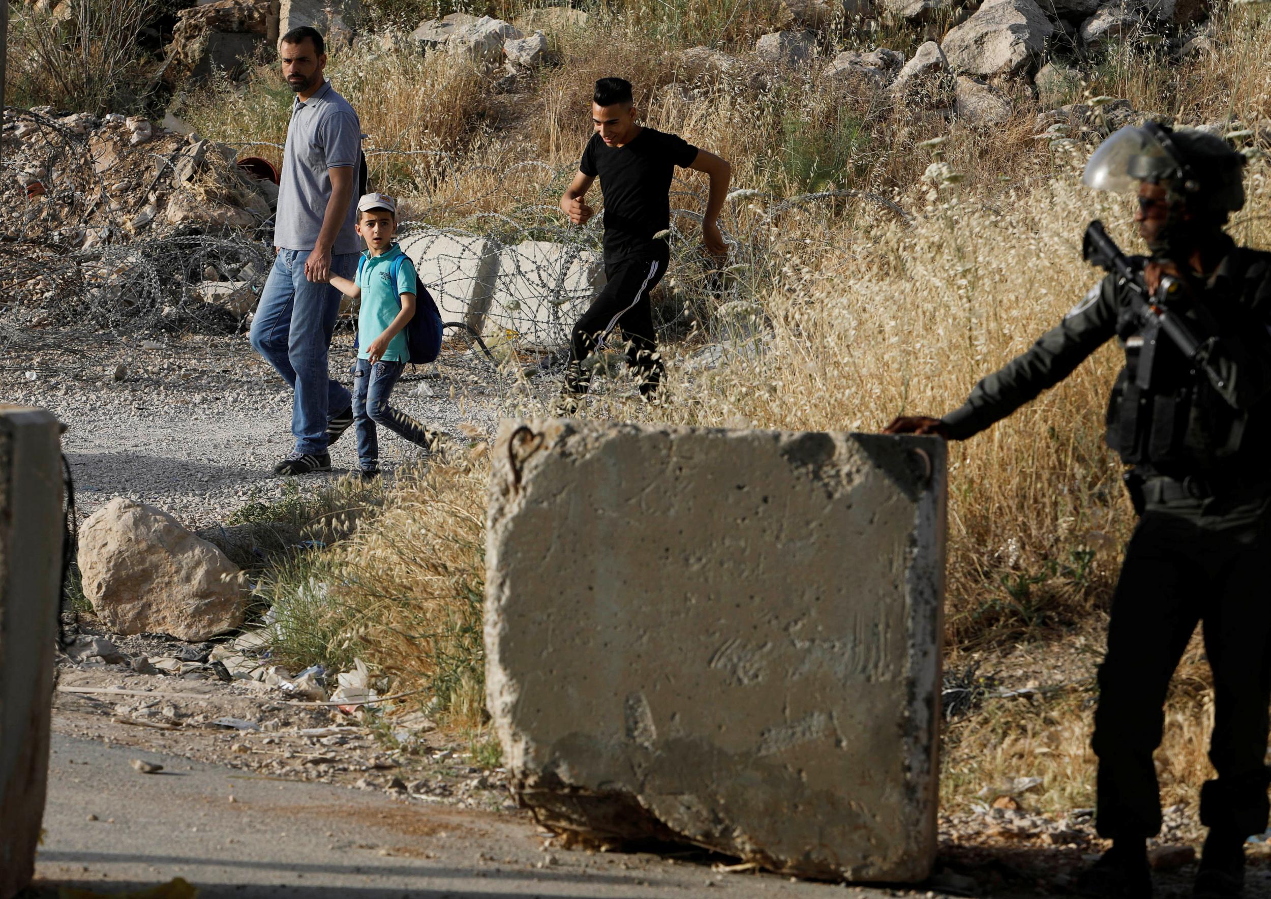 A border officer stands guard as Palestinians make their way to prayer near Ramallah in the Israeli-occupied West Bank