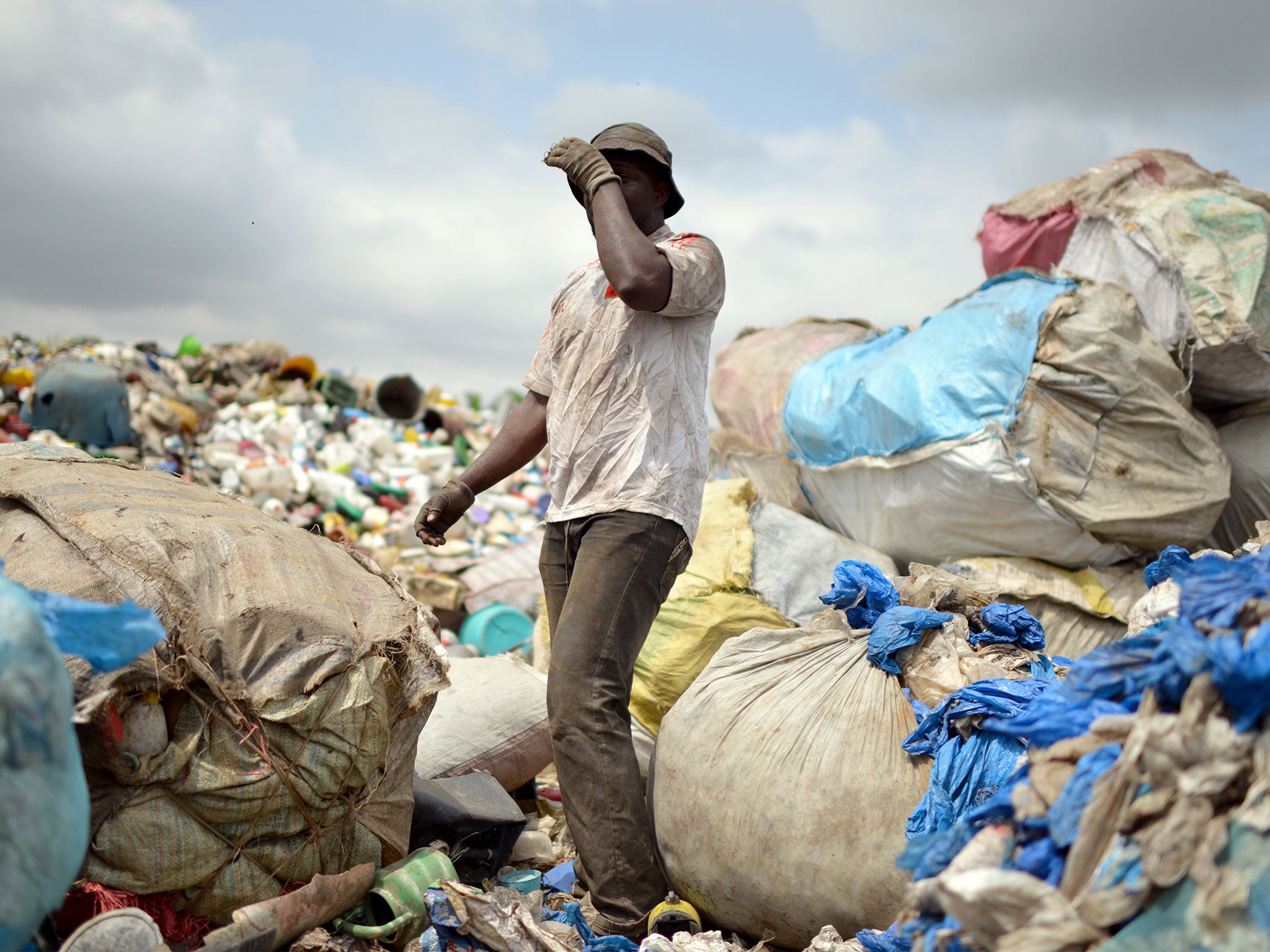 A man stands among plastic bags at a garbage dump in Abidjan, Ivory Coast